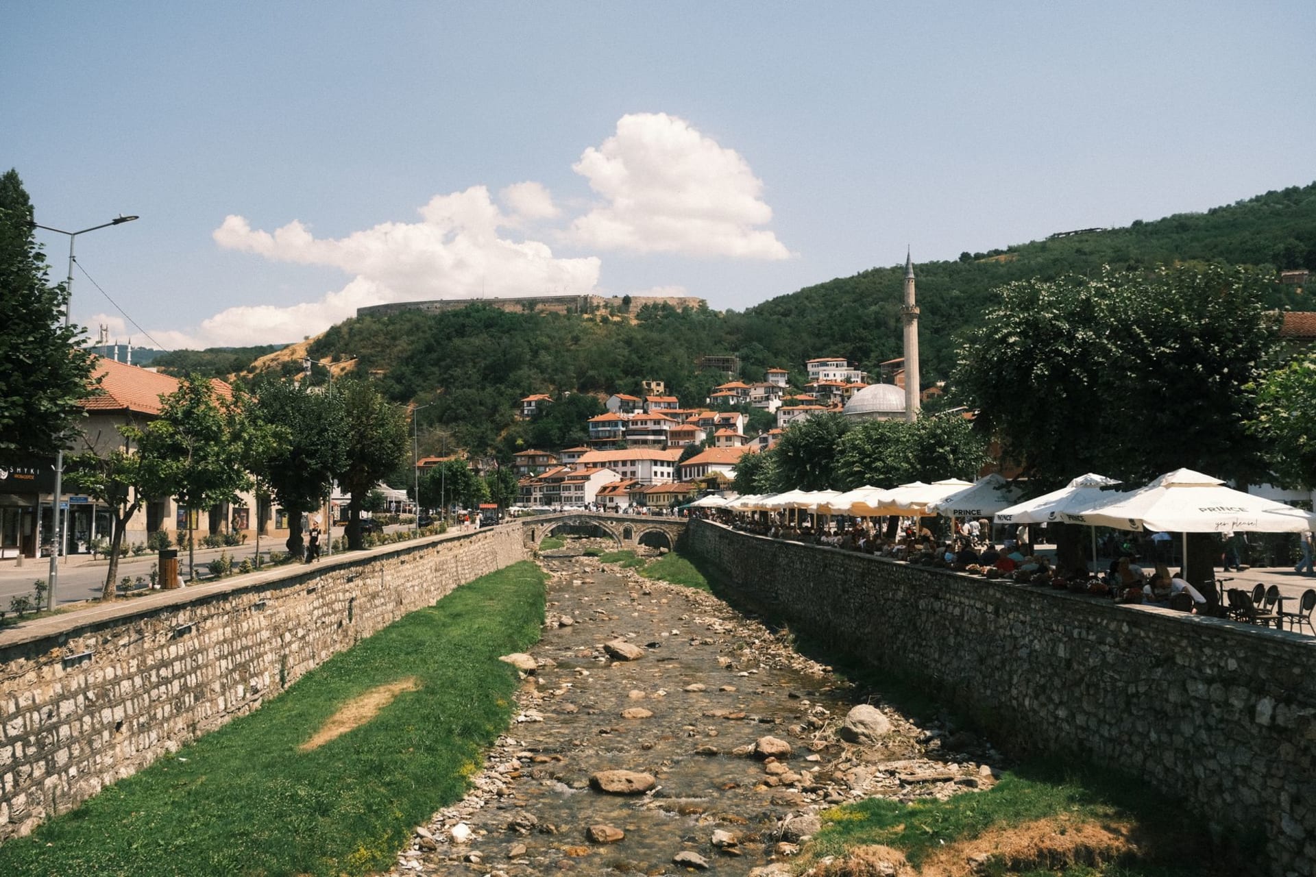 Panoramic view of Prizren's charming riverside cafes and historic Ottoman architecture on a sunny day, photo by Muhammed Fatih Beki