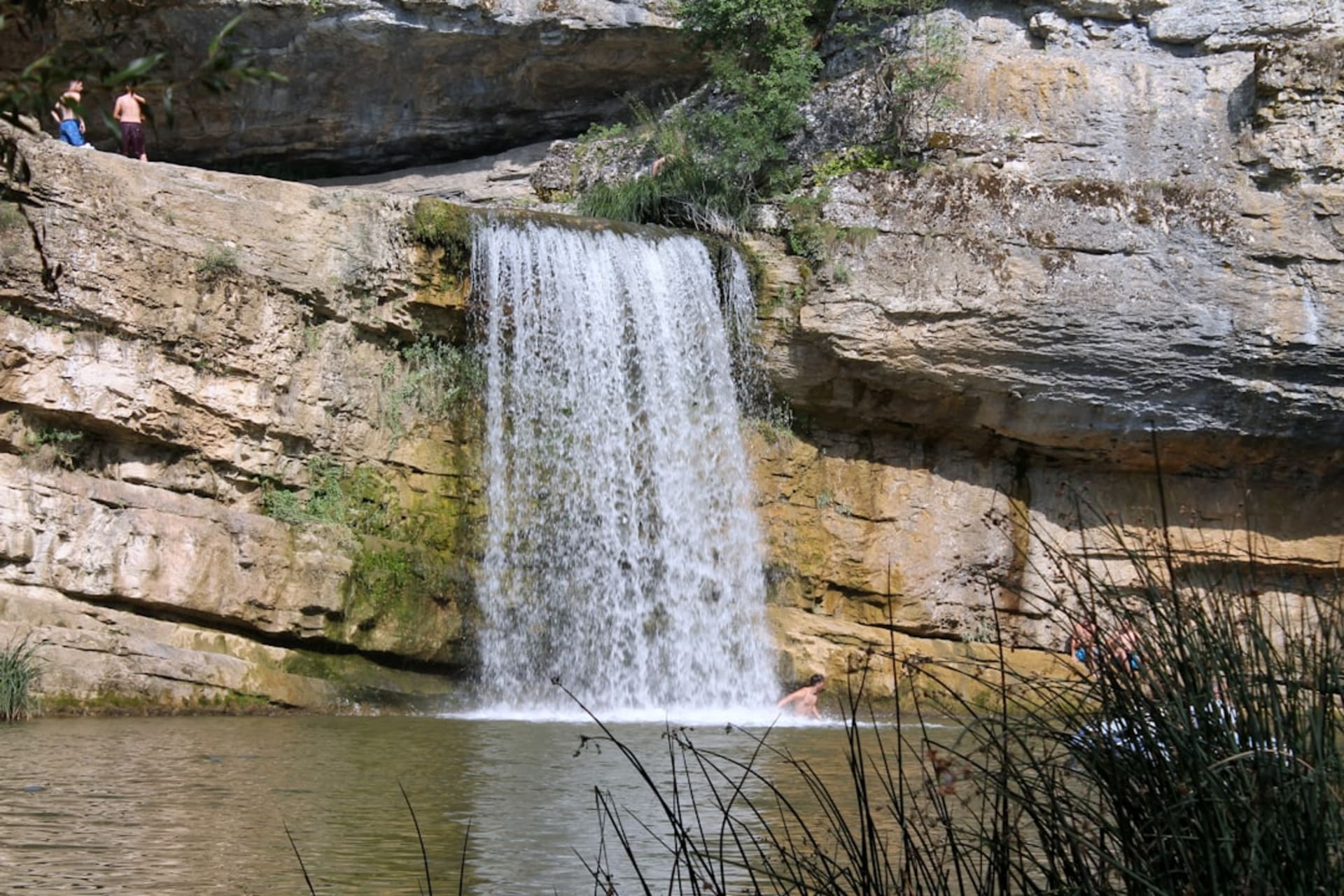Eau vert émeraude cascadant entre des vasques calcaires dans le canyon de Mirusha, Kosovo, lumière solaire filtrant à travers la gorge