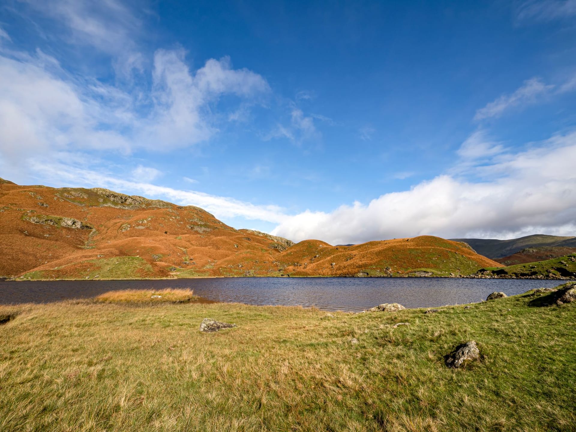 Grasmere village and its lake in autumn with golden fells rising behind the stone cottages
