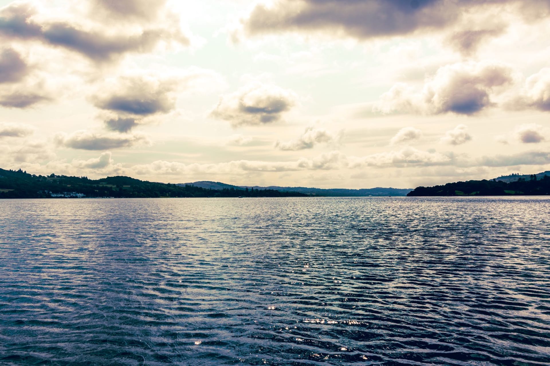 Peaceful Lake Windermere with calm waters reflecting dramatic clouds, Lake District, England