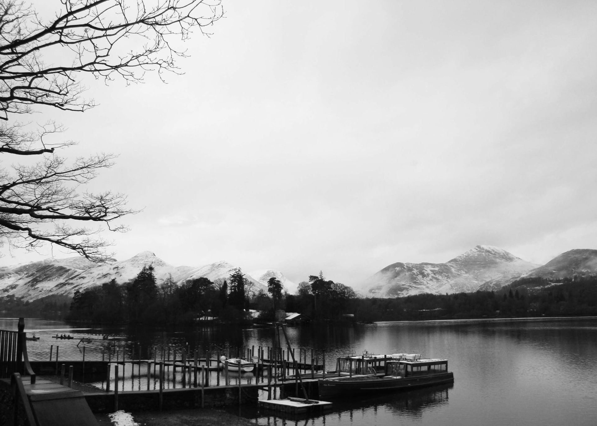 Windermere lake at dawn with still water reflecting pink clouds and distant fells