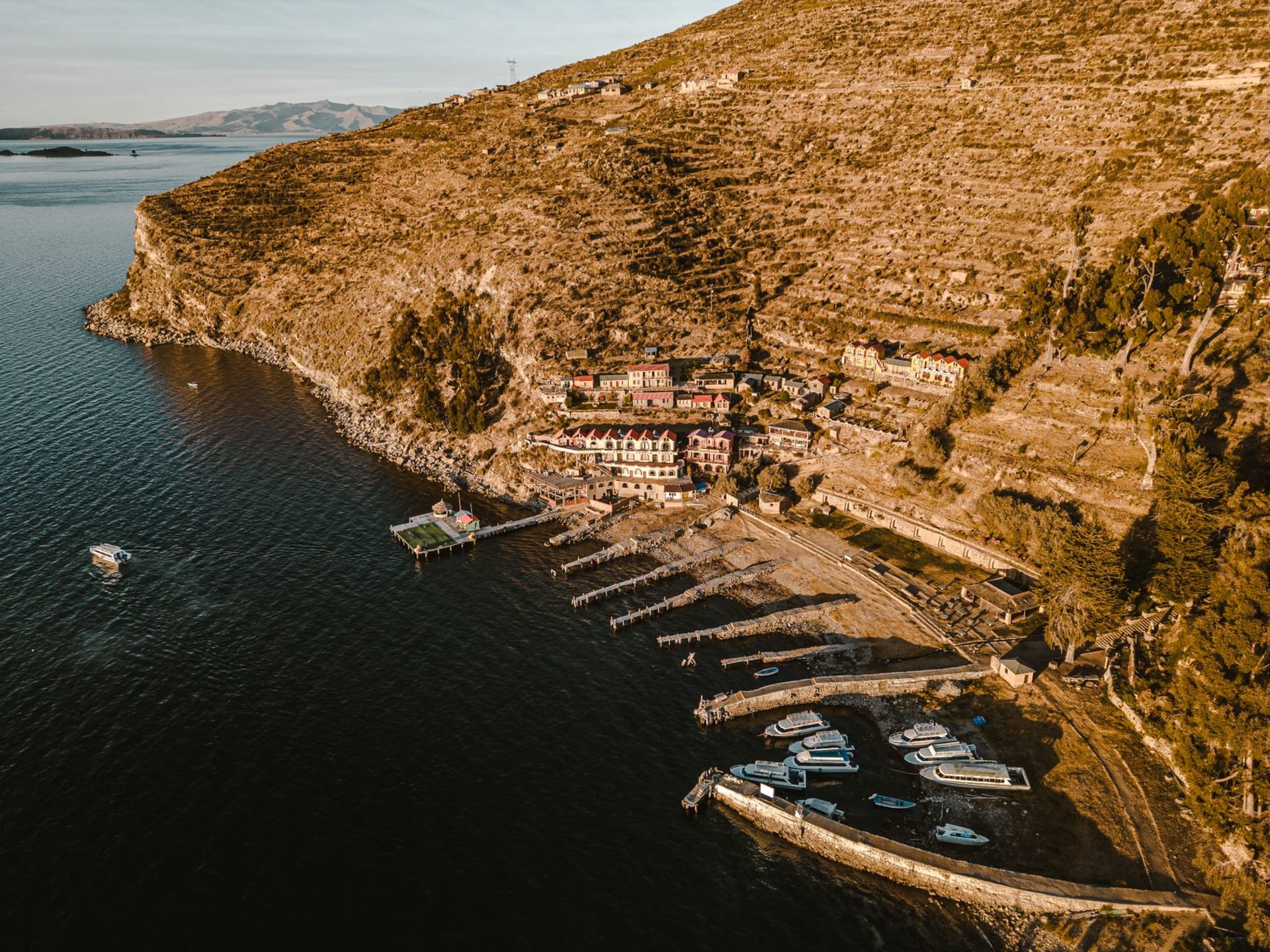 The terraced green slopes of Isla de la Luna rising from the deep blue of Lake Titicaca under a vast altiplano sky