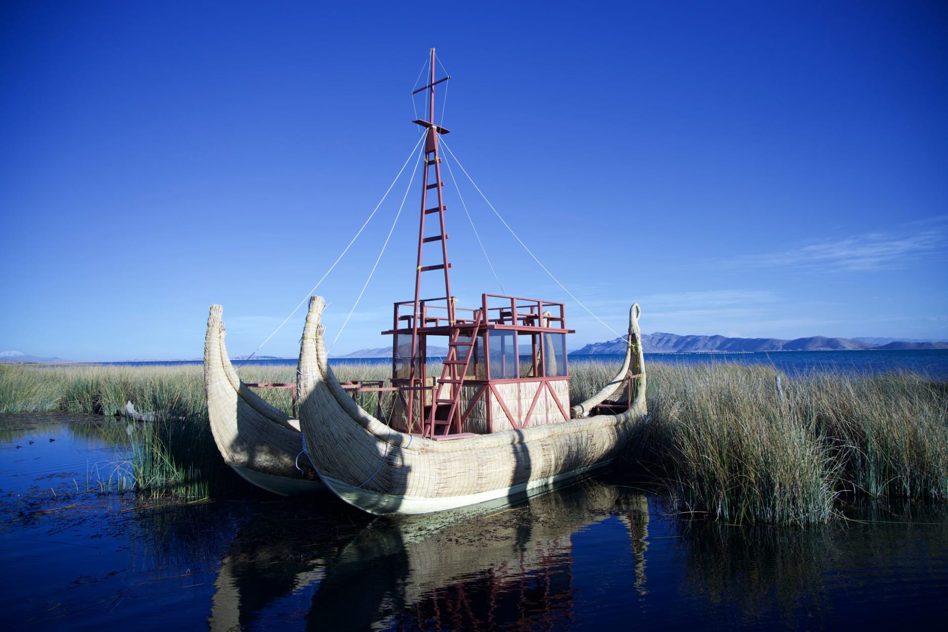 Traditional reed totora boat on the still blue surface of Lake Titicaca under a wide open sky