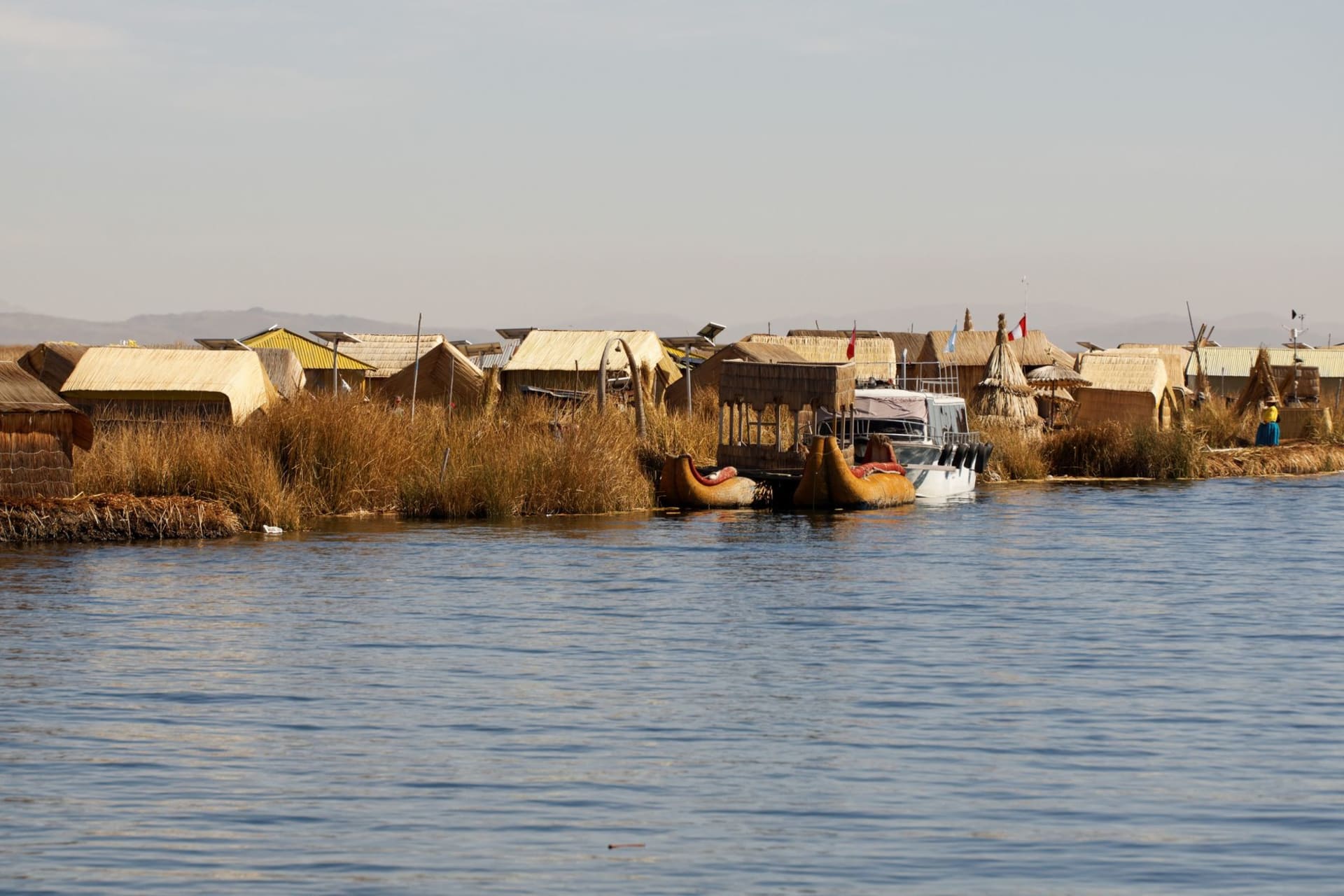 Small wooden fishing boats on the glassy waters of Lake Titicaca at dawn near the Llachón peninsula, with Andean peaks reflected in the still surface