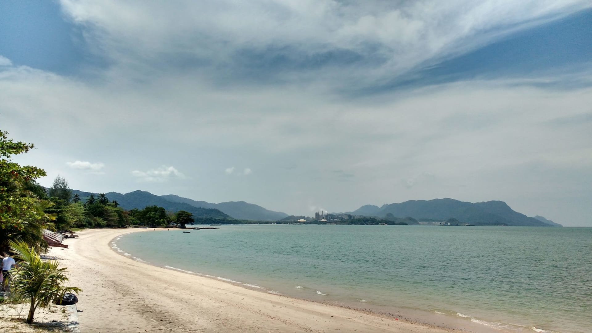 Sandy beach with clear turquoise water and palm trees under a bright blue sky in Langkawi, Malaysia