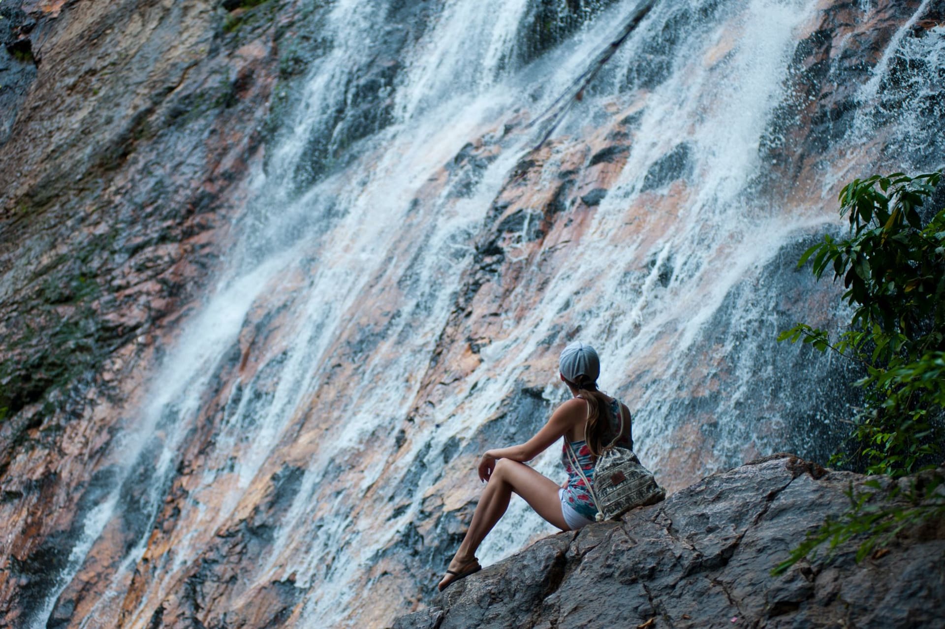 Temurun Waterfall cascading down a tall limestone cliff face into a dark jungle pool, sunlight filtering through the forest canopy above, no other visitors visible