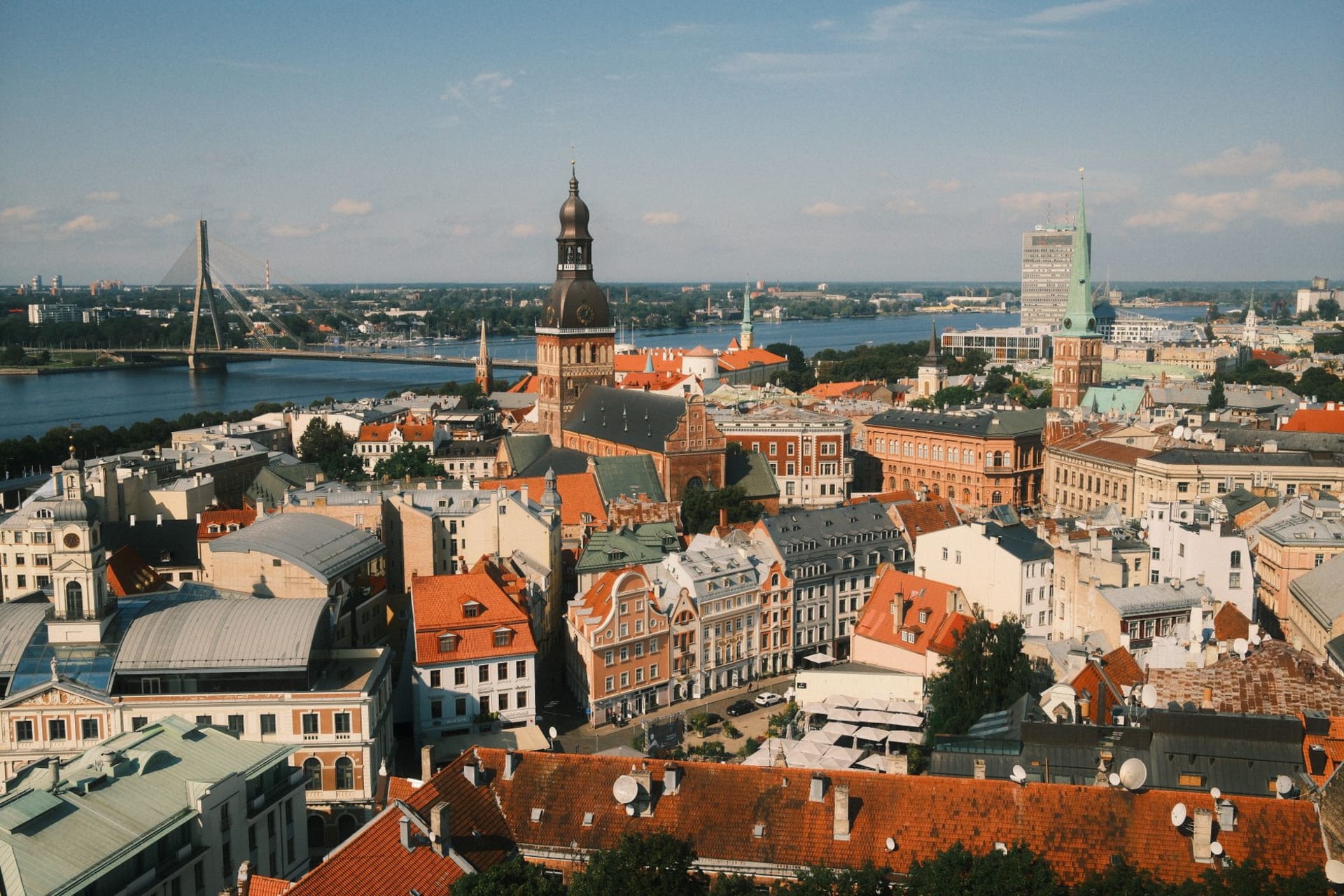 Aerial view of Riga's historic old town with its red-tiled rooftops and church spires rising above the Daugava River at dusk