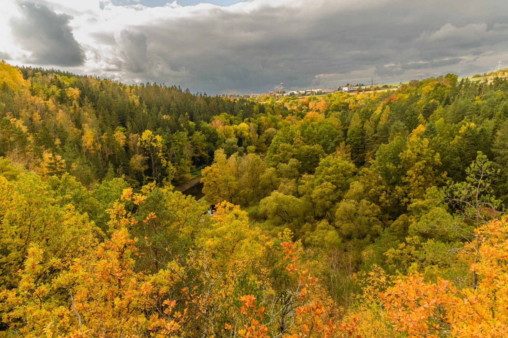 Turaida Castle's red brick tower rising above the autumn-gold Gauja River valley, viewed from the cable car crossing