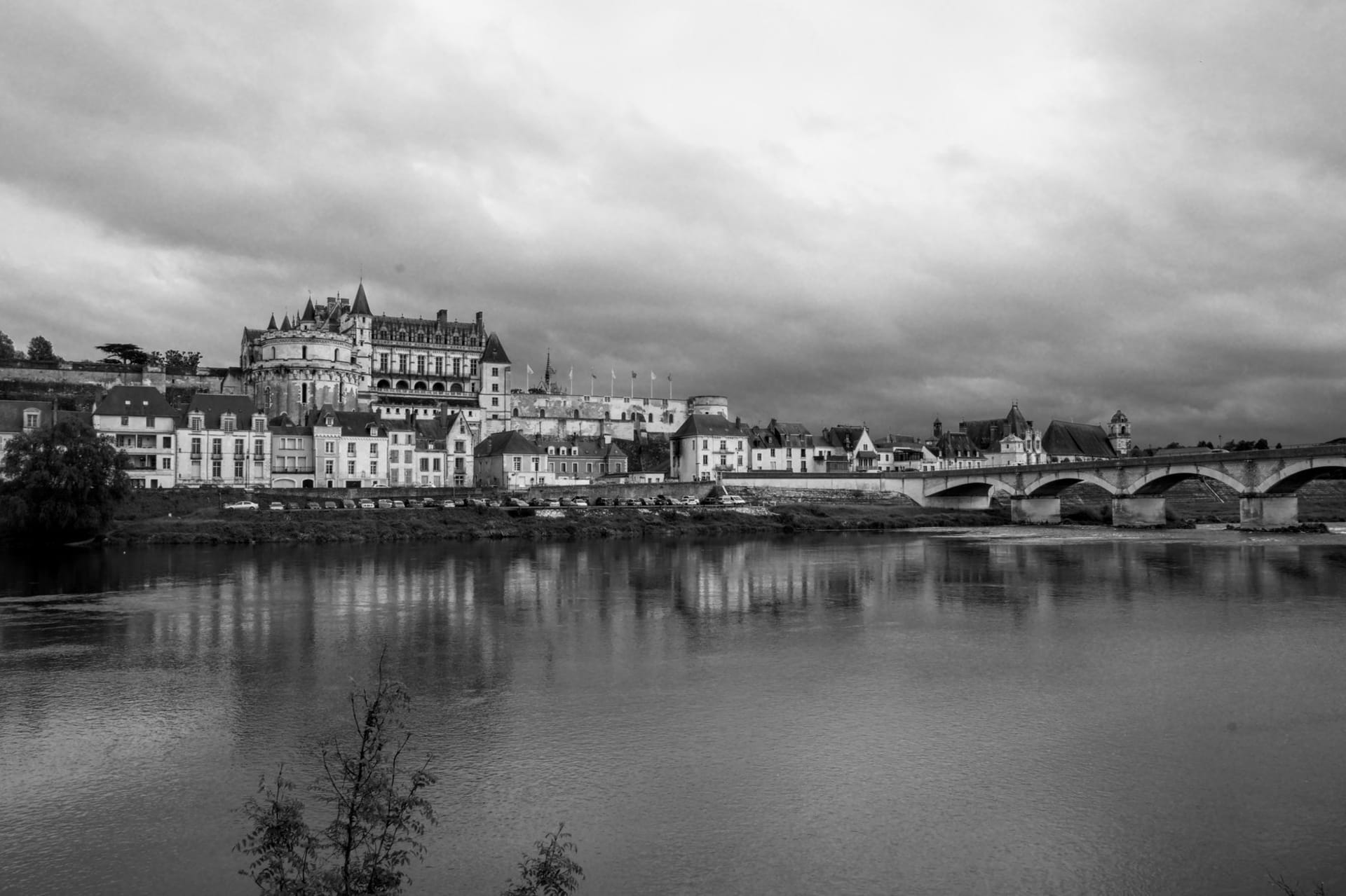 The Château Royal d'Amboise rising above the Loire river at dusk, its twin towers silhouetted against a pale amber sky