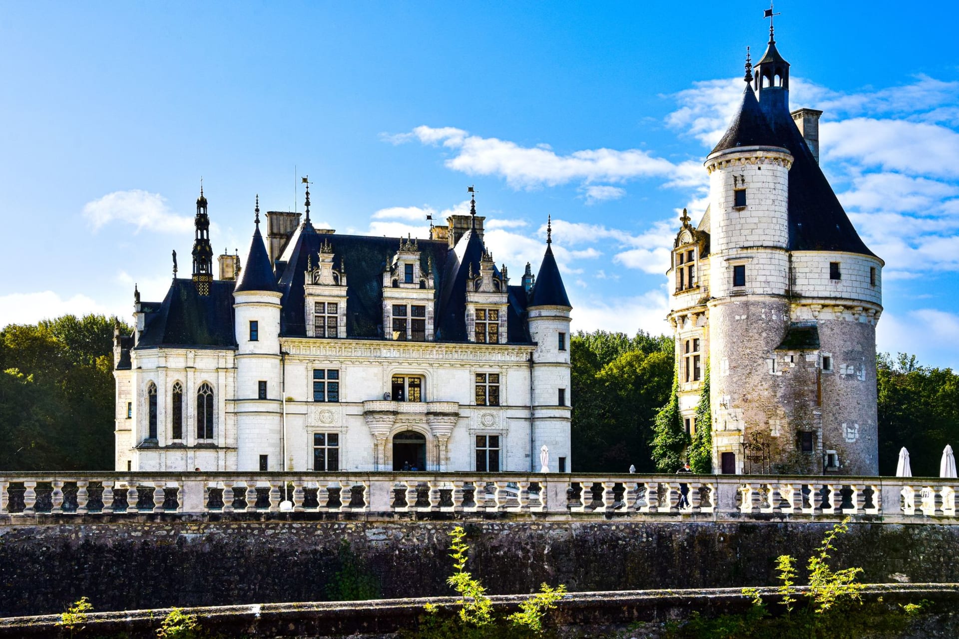 Château de Chenonceau spanning the Cher river, its arched stone bridge reflected in the calm water below