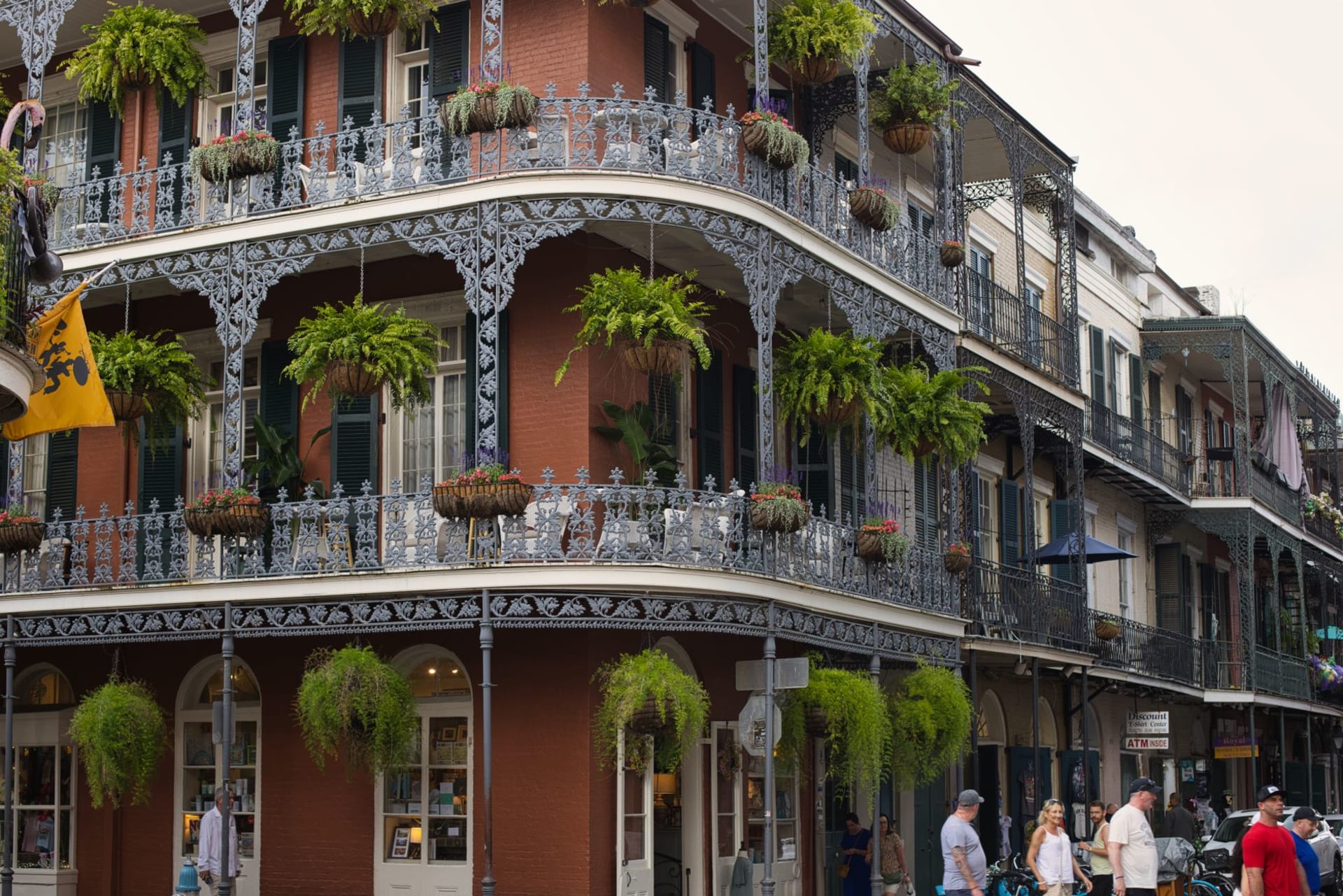 Wrought-iron balconies draped in jasmine and fern on a gas-lit Royal Street in the French Quarter at night