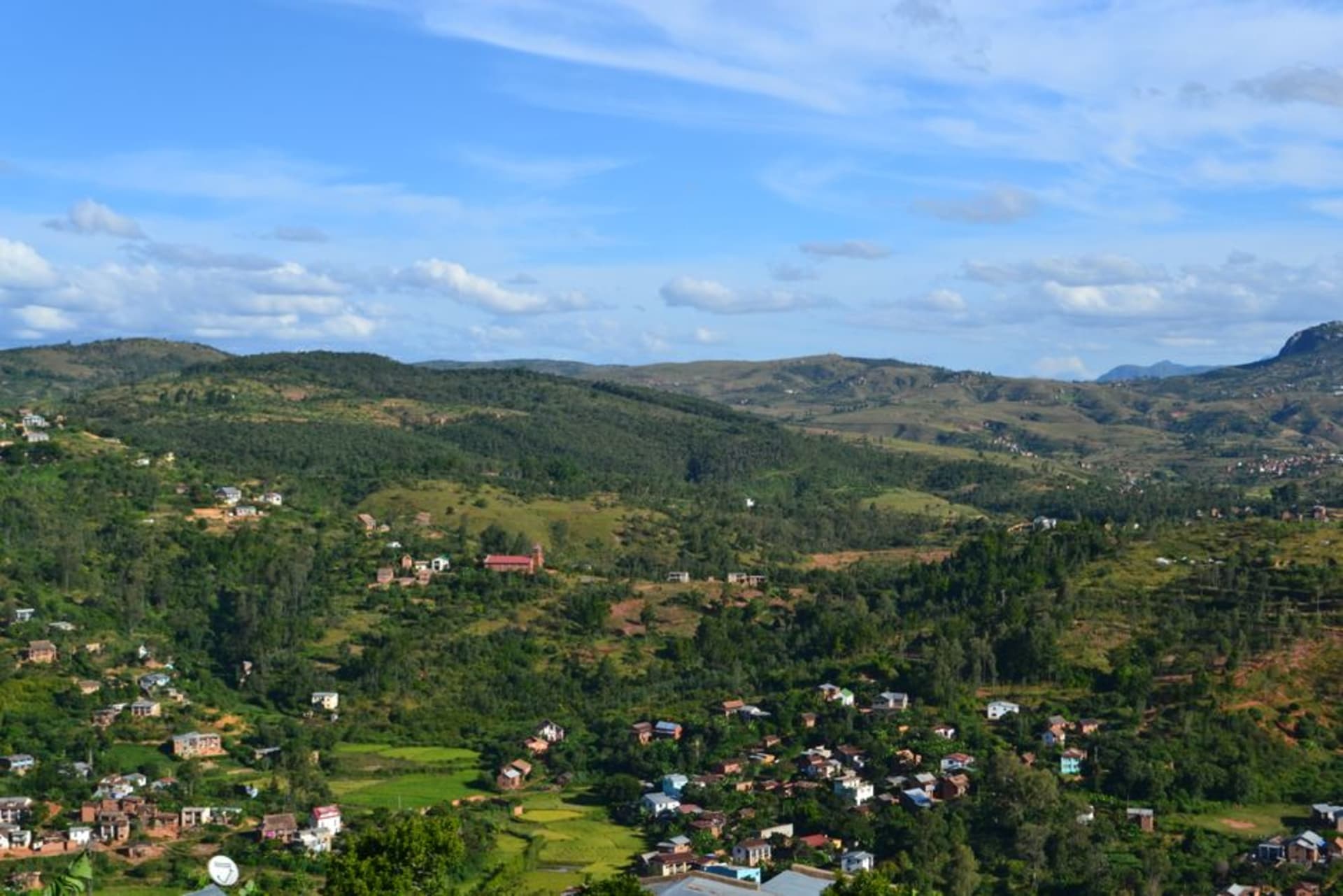 The old hillside quarter of Fianarantsoa with narrow stone streets and colonial-era buildings, terraced vineyards visible on the surrounding hills