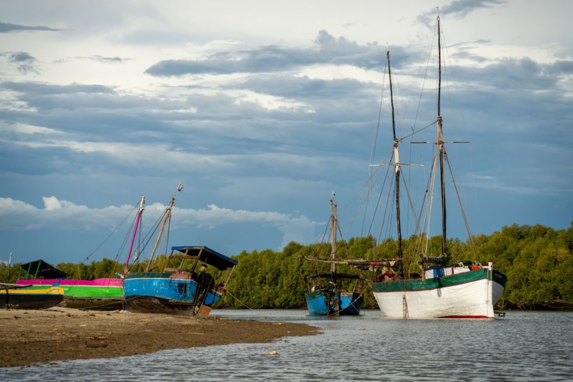 Un tramo tranquilo del Canal de Pangalanes en la hora dorada, palmeras bordeando las orillas y una canoa de madera flotando sobre el agua quieta