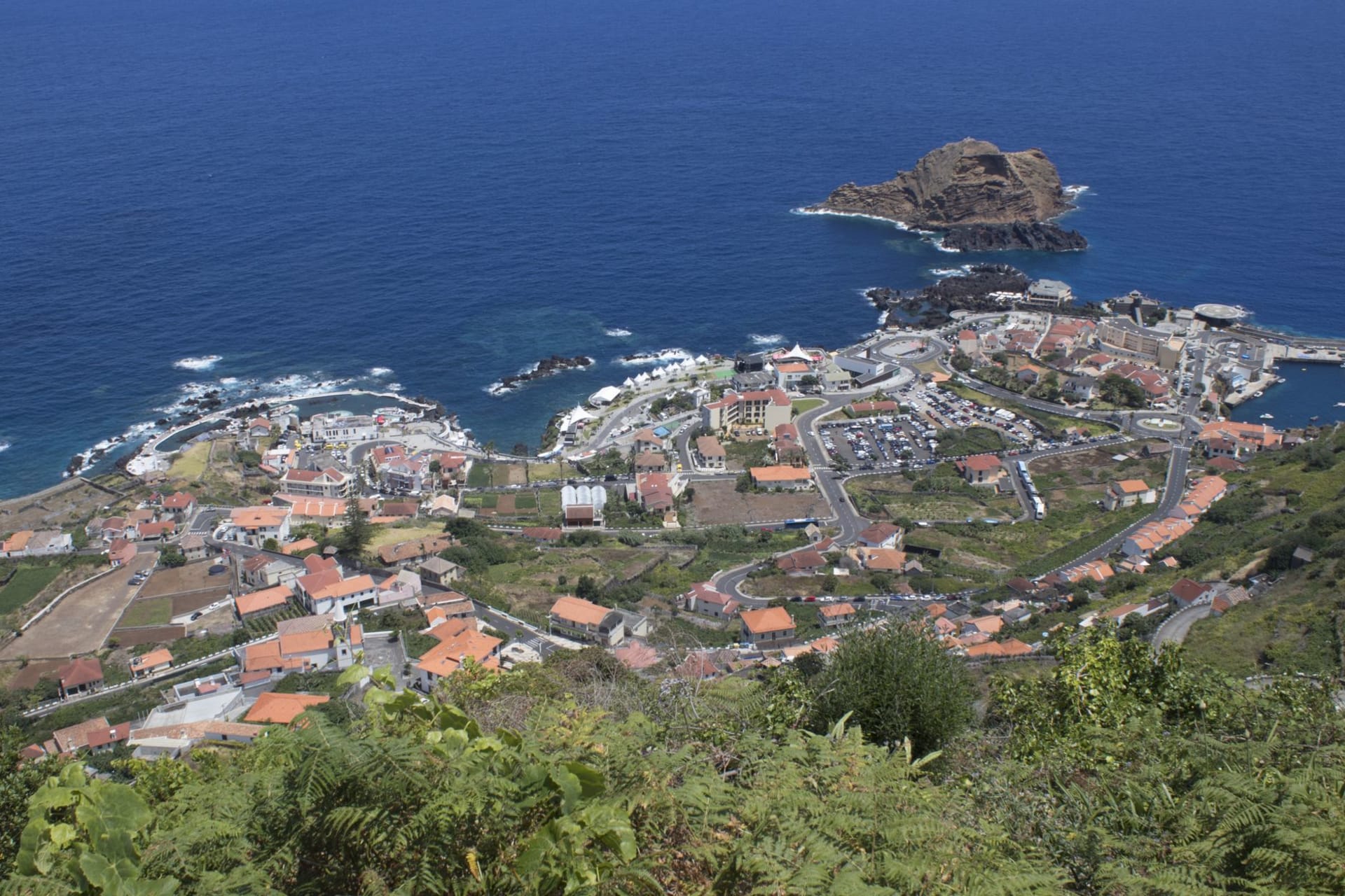 Small fishing boats in the harbour at Caniçal with volcanic cliffs and open Atlantic beyond, eastern Madeira