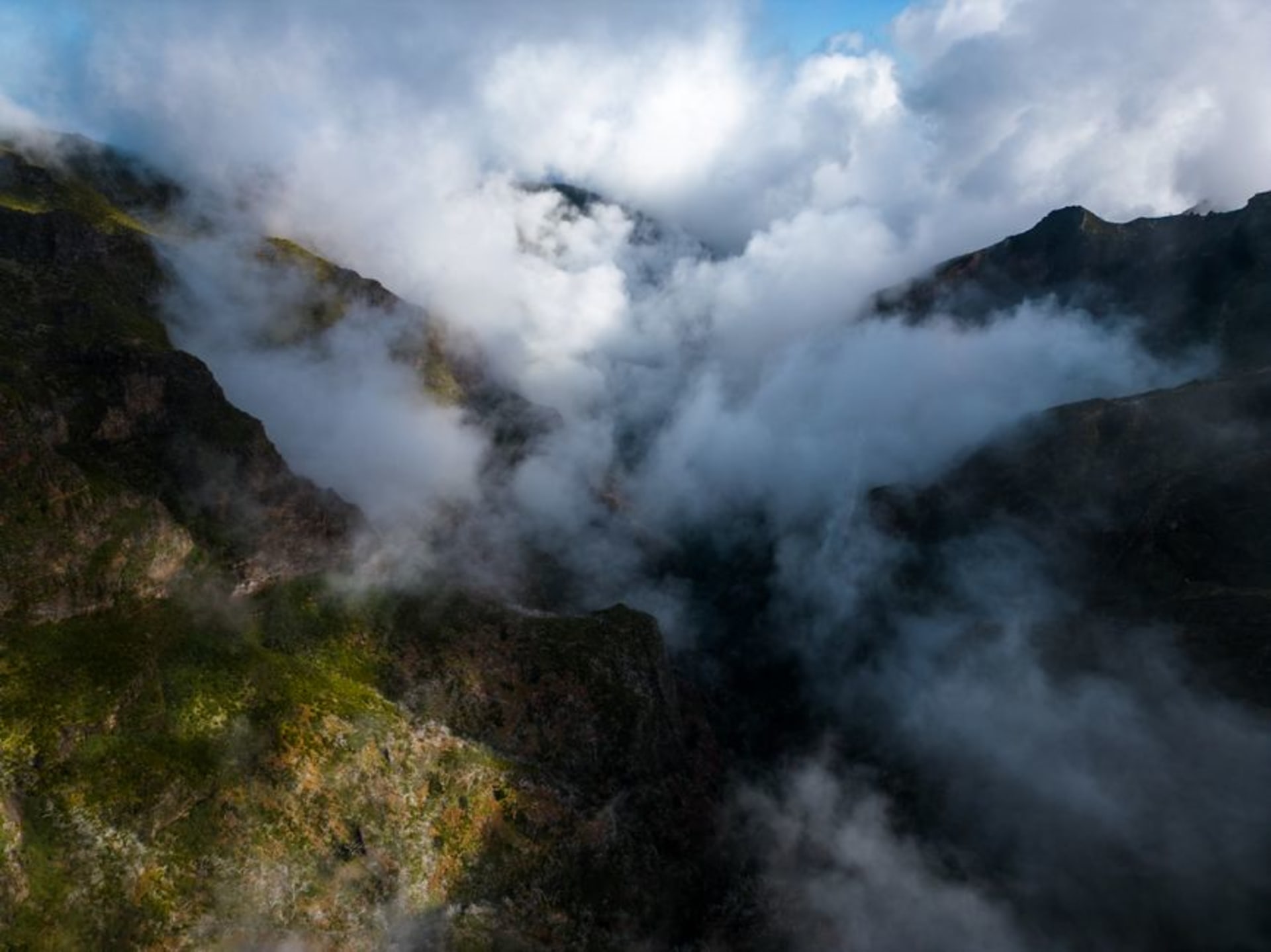 The village of Curral das Freiras nestled at the bottom of a green volcanic crater, surrounded by steep Madeiran peaks