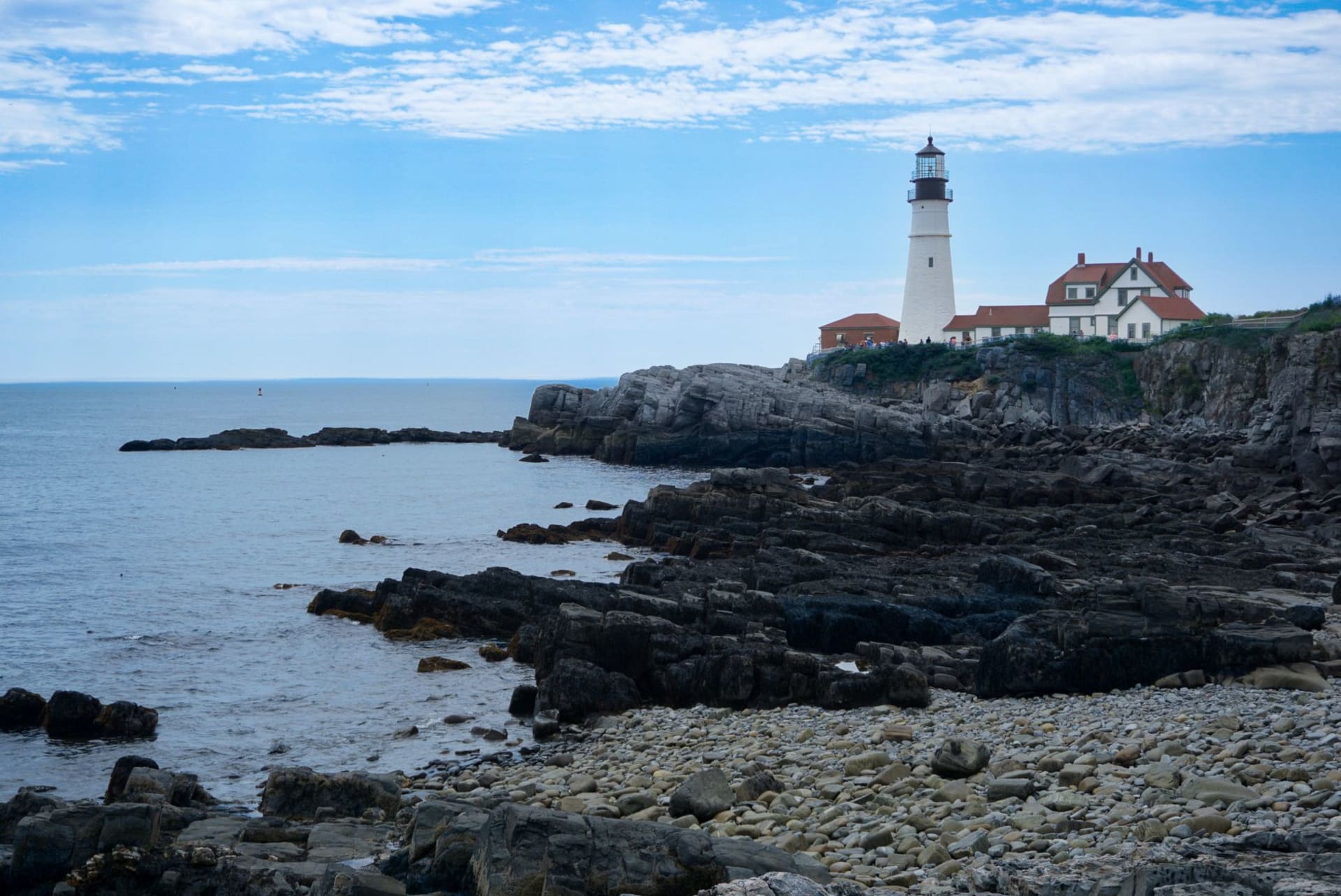 Portland Head Light standing on the rocky Cape Elizabeth shoreline beneath a clear blue sky