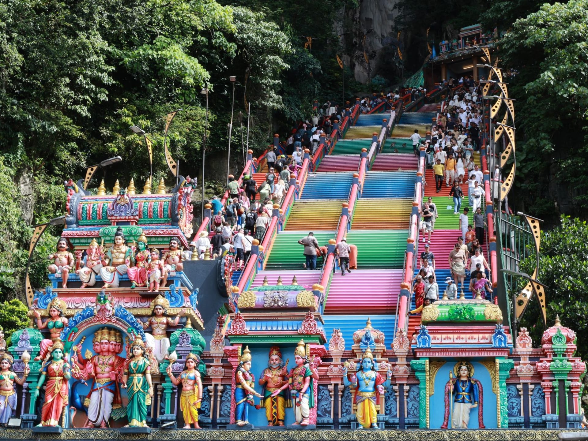 The towering golden statue of Murugan beside the rainbow-painted 272 steps leading up to the Batu Caves temple, Kuala Lumpur