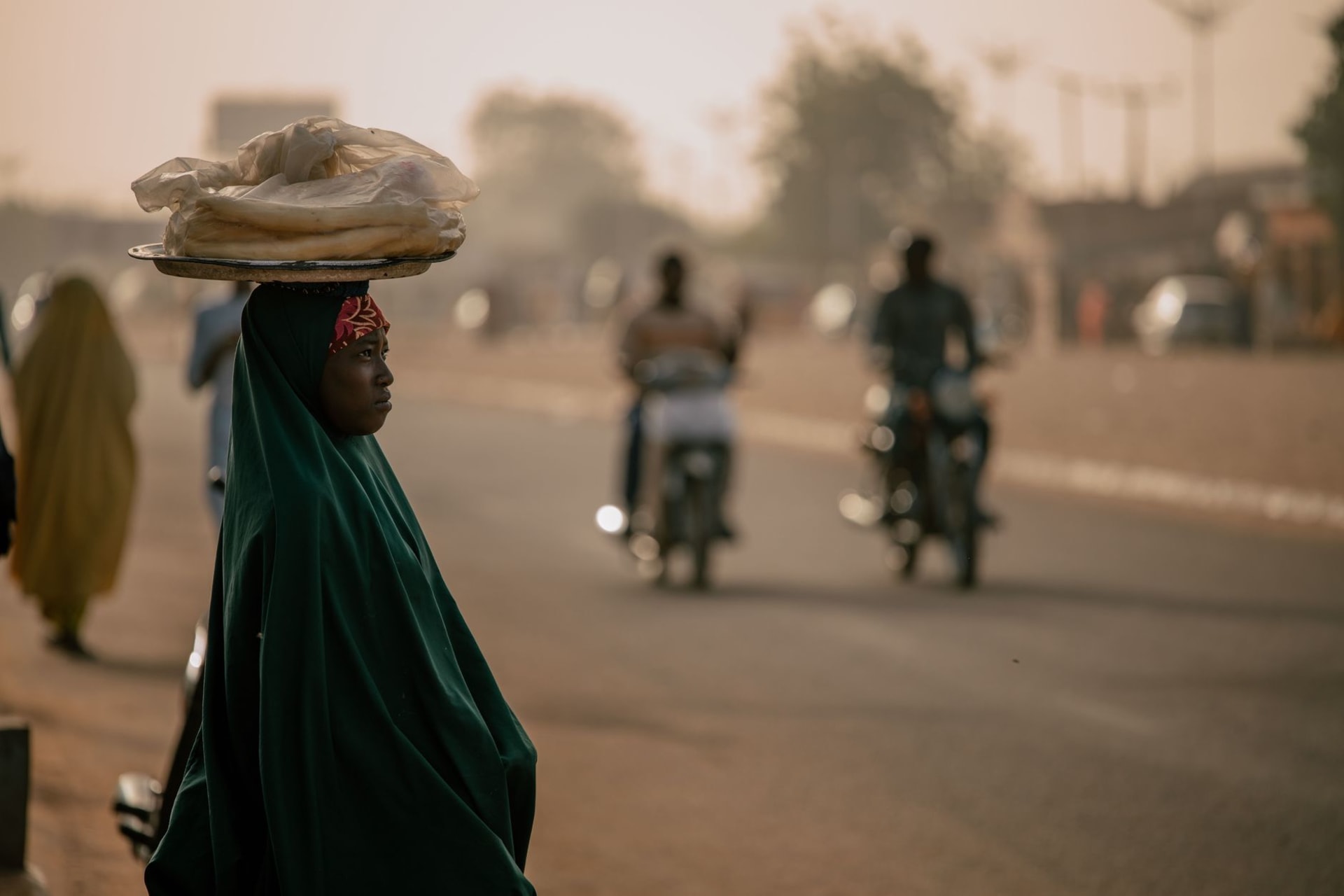 Des pirogues en bois alignées le long du fleuve Niger au coucher du soleil, la skyline de Bamako brillant en orange derrière elles