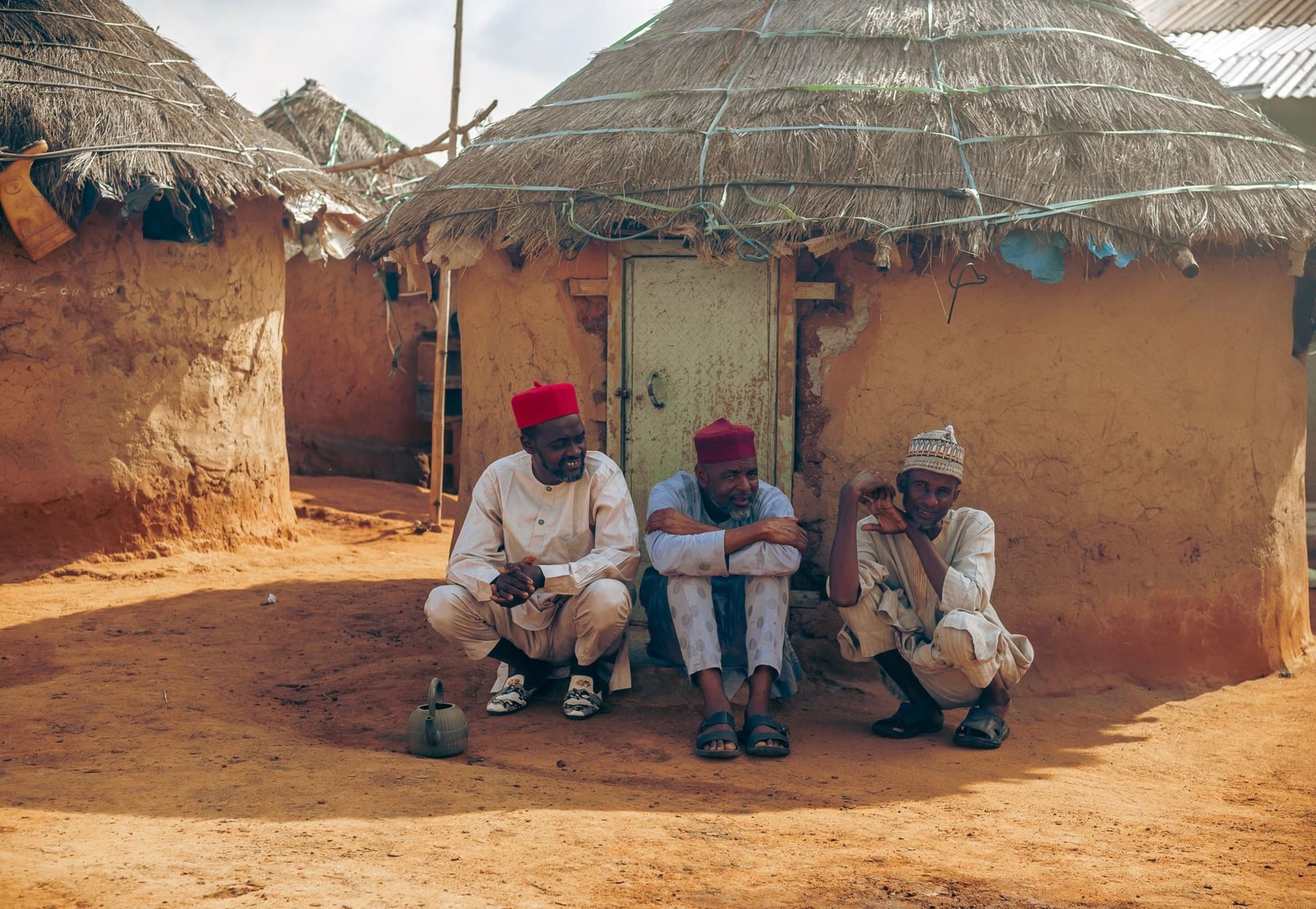 Casas de una aldea dogón construidas en la cara del Escarpe de Bandiagara al amanecer, acantilados de arenisca roja elevándose sobre ellas