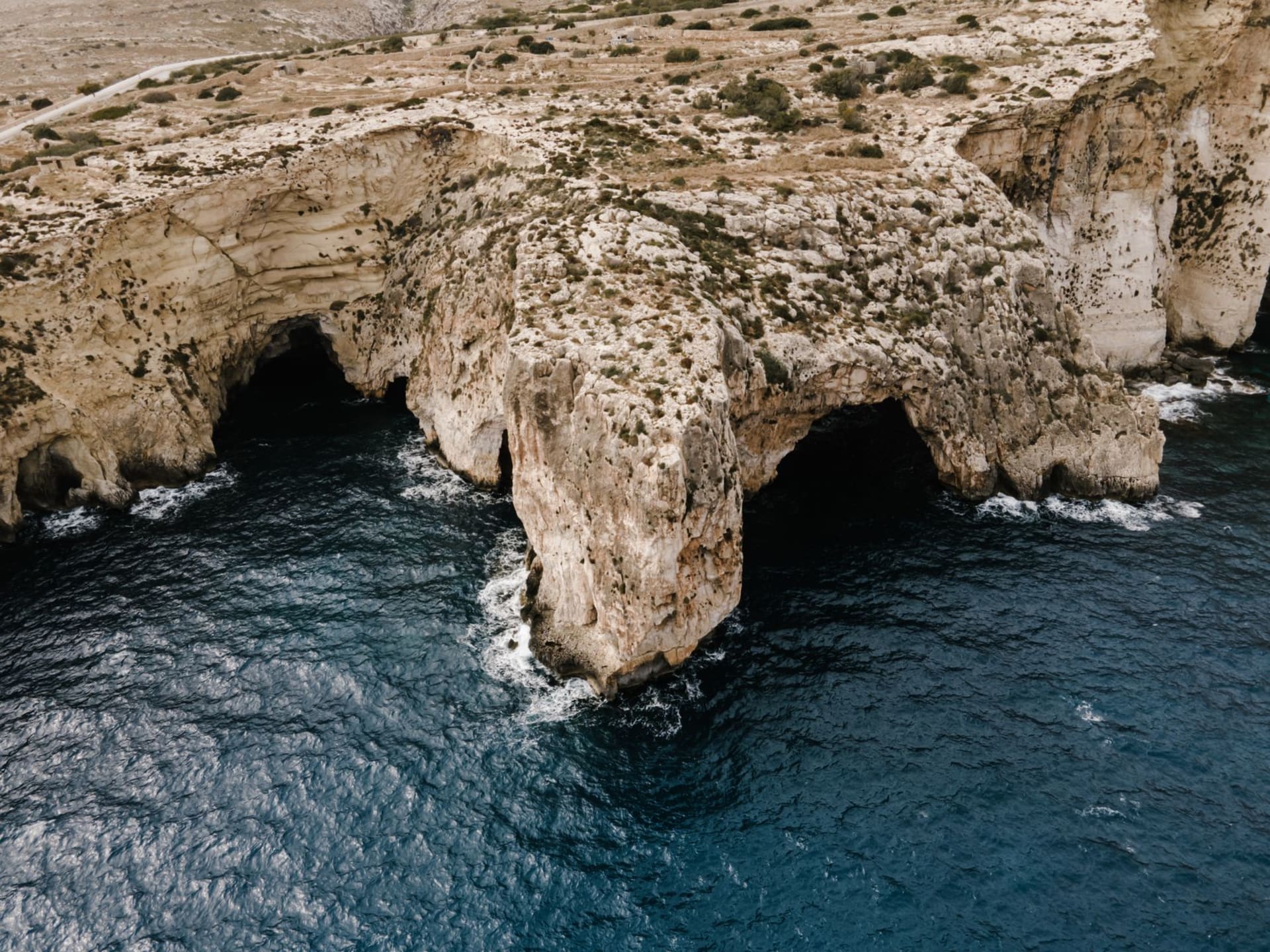 Sunlit sea cave at Blue Grotto Malta with electric blue water reflecting off limestone walls