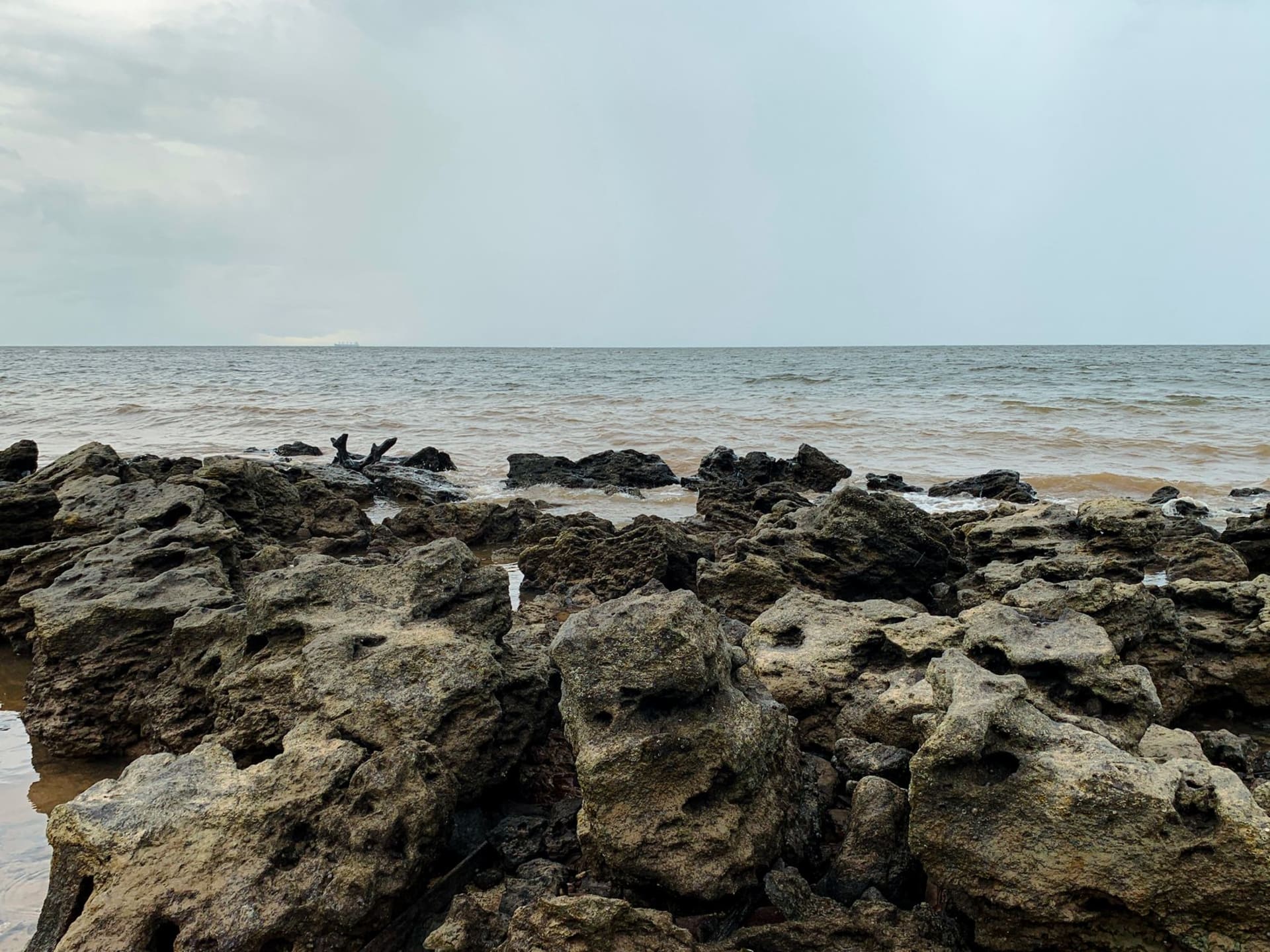 Wooden riverboats moored along the muddy waterfront of Ponta de Pedras on Marajó Island under a heavy tropical sky