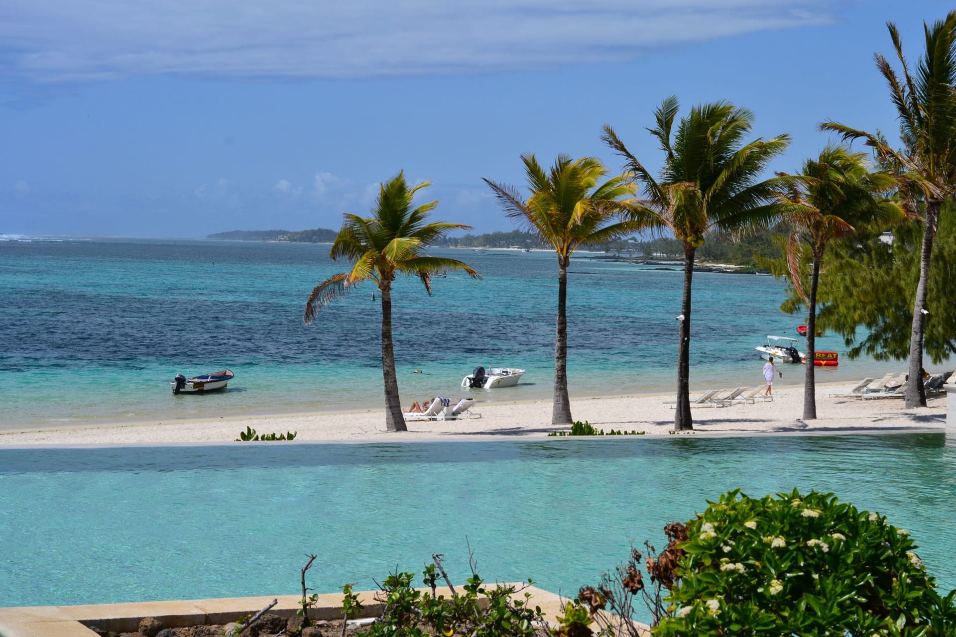 Flic en Flac beach at sunset, the sky turning orange and pink above a calm turquoise lagoon with palm trees