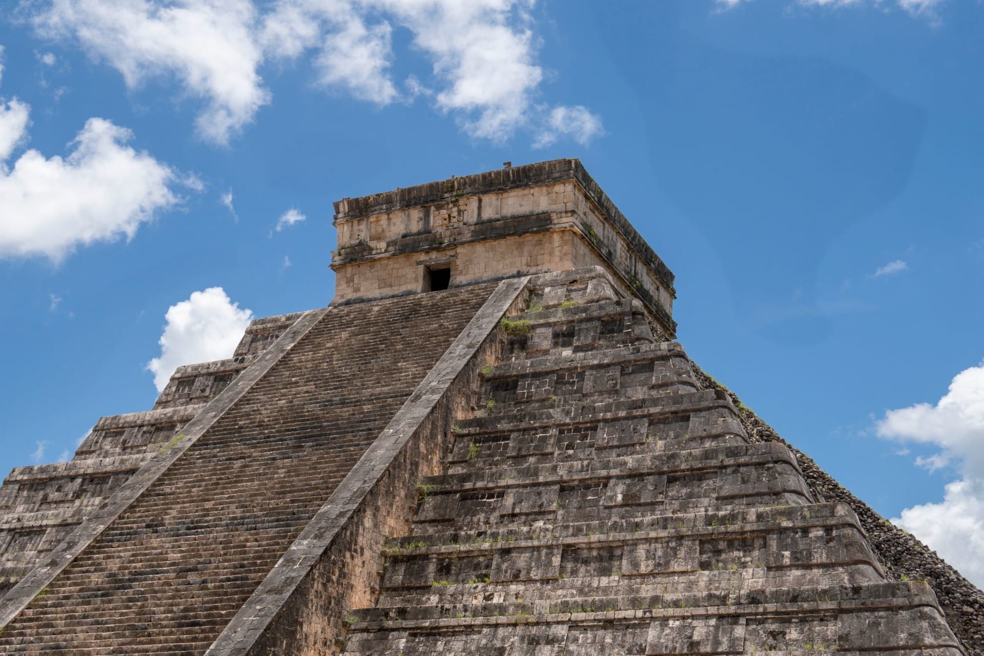 El Castillo pyramid at Chichen Itza rising in the pale morning light before the crowds arrive, perfectly symmetrical against a clear sky