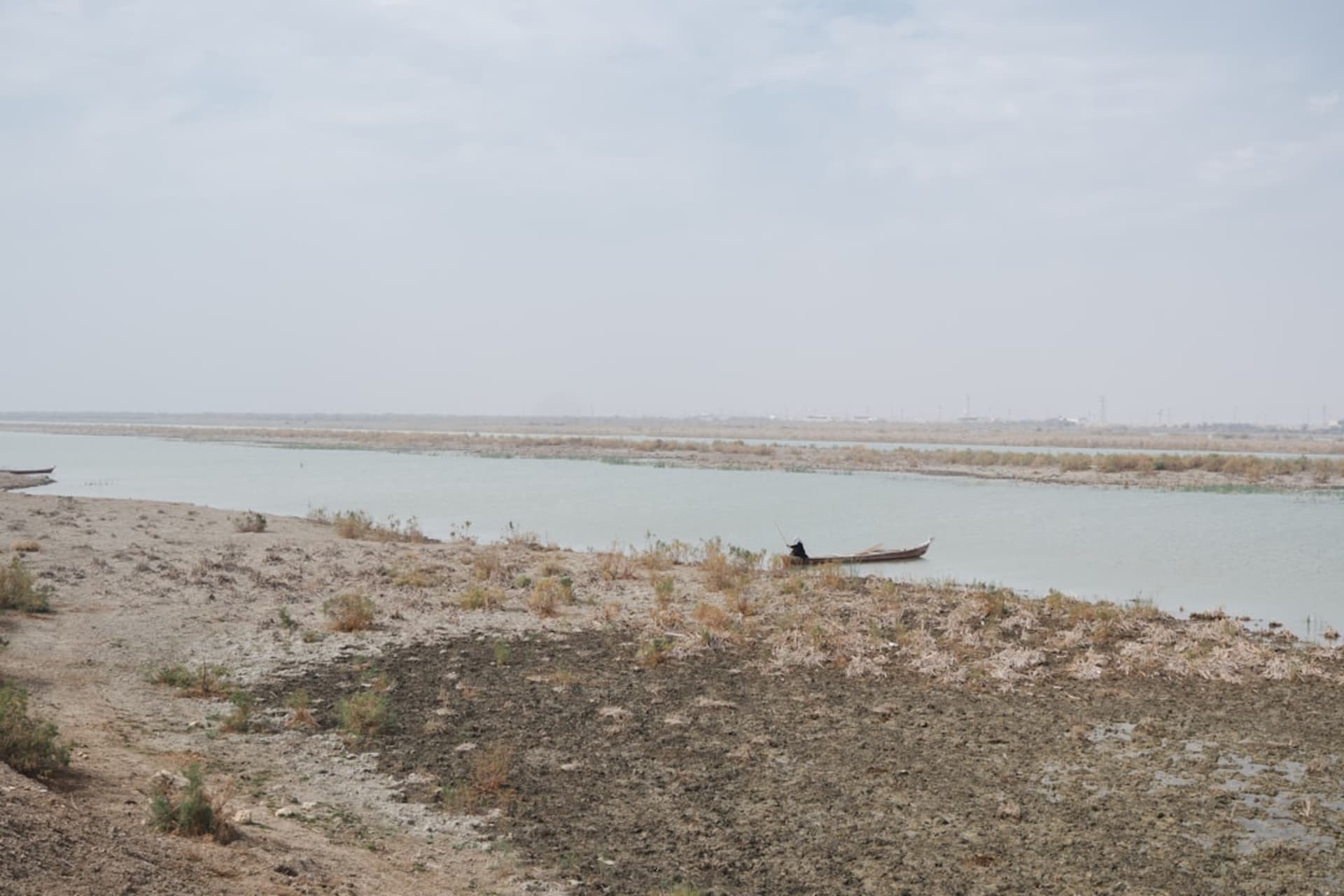 La confluencia de los ríos Tigris y Éufrates en Al-Qurnah, agua parda fundiéndose en el ancho Shatt al-Arab, palmeras bordeando ambas orillas