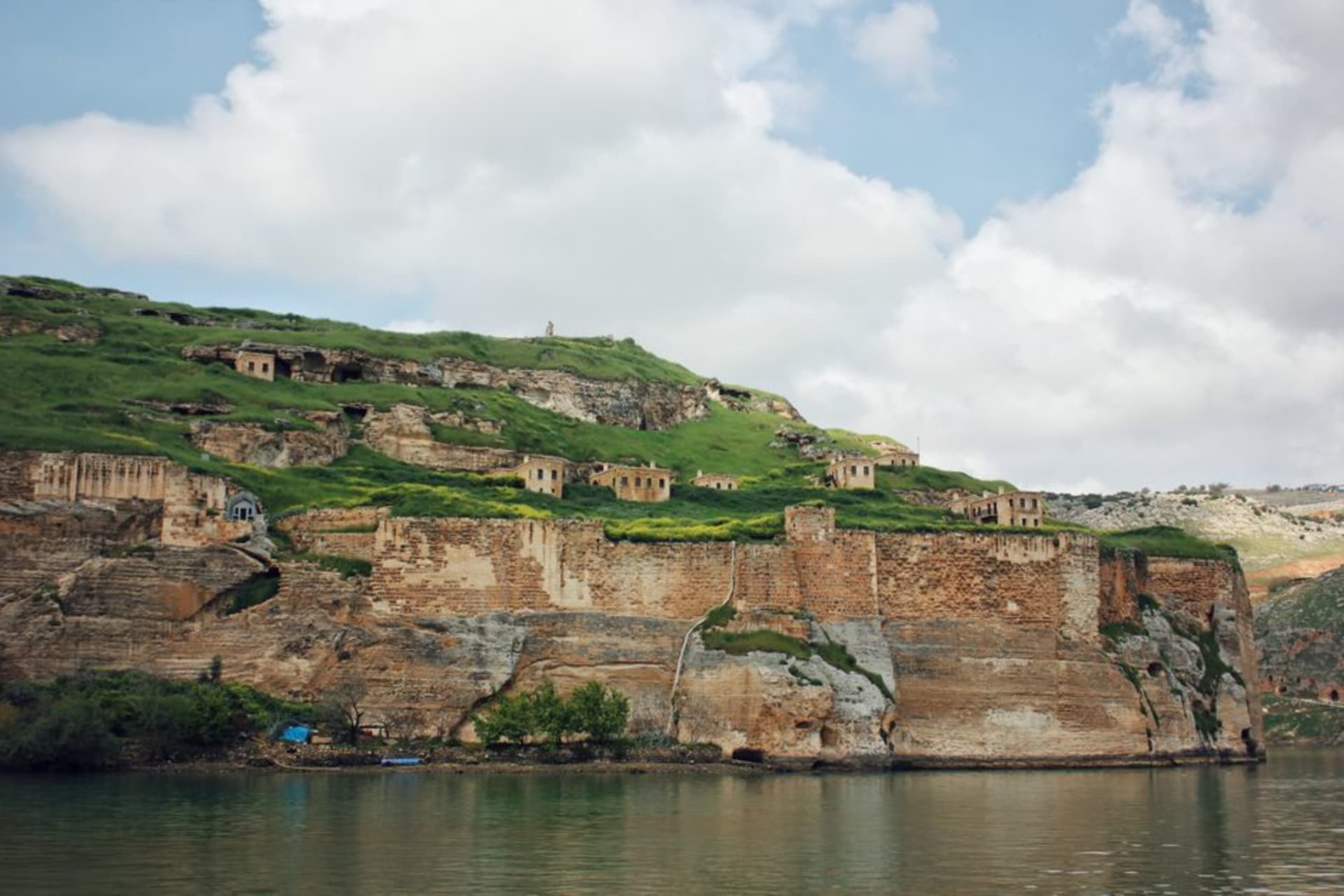 The ruins of the Ziggurat and temple complex of Ashur perched on a limestone bluff above a bend in the Tigris River, with the water visible far below