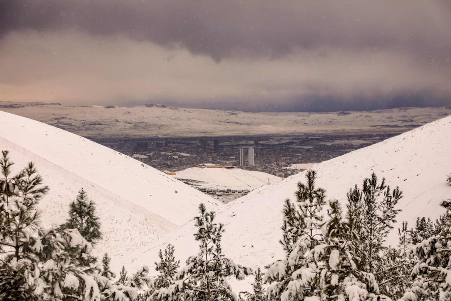La ville de Sulaymaniyah étalée sur le fond d'une vallée, les montagnes kurdes environnantes s'élevant abruptement derrière elle sous un ciel dégagé