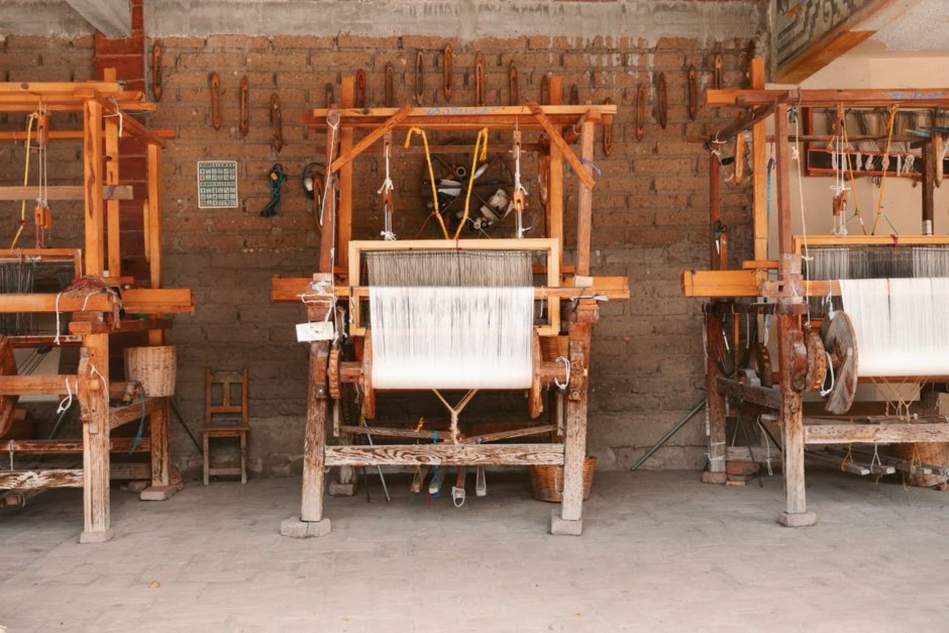 Artisan hands splitting palm strips in a weaving workshop in Acatlán de Osorio, morning light crossing a concrete floor
