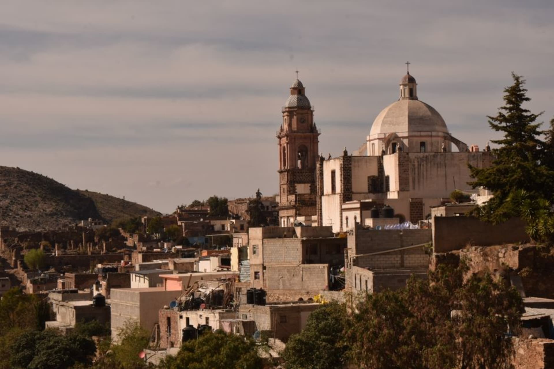 The honey-colored stone facade of the Parroquia de Nuestra Señora de la Asunción rising above Armadillo de los Infante's sun-washed plaza on a clear winter afternoon.