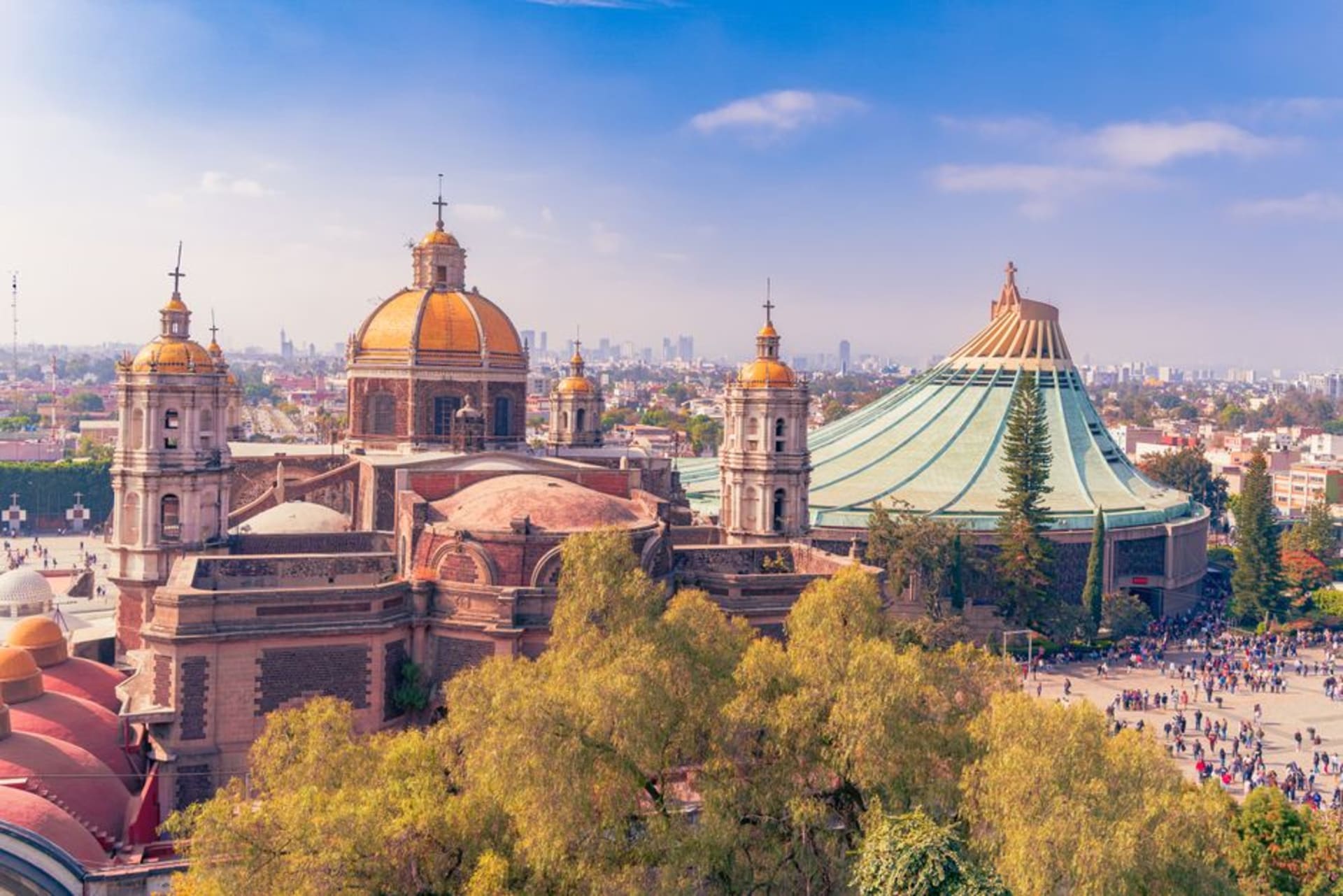 The modern circular Basílica de Guadalupe with the tilted colonial Antigua Basílica behind it and the Cerro del Tepeyac rising above the complex