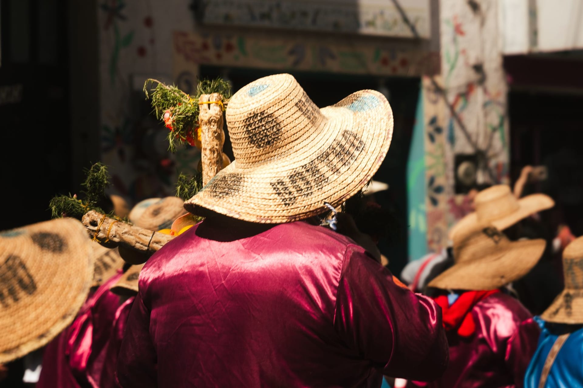 A display of handmade wooden toys and carved masks in a Cofradía de Suchitlán workshop — painted birds, jaguar faces, and small painted animals arranged on a wooden table with coffee plantations visible through the window