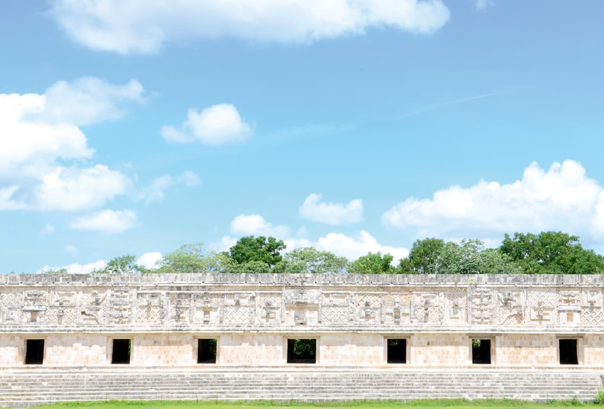 The Temple of the Seven Dolls at Dzibilchaltún, pale limestone rising above the flat Yucatán scrub in early morning light