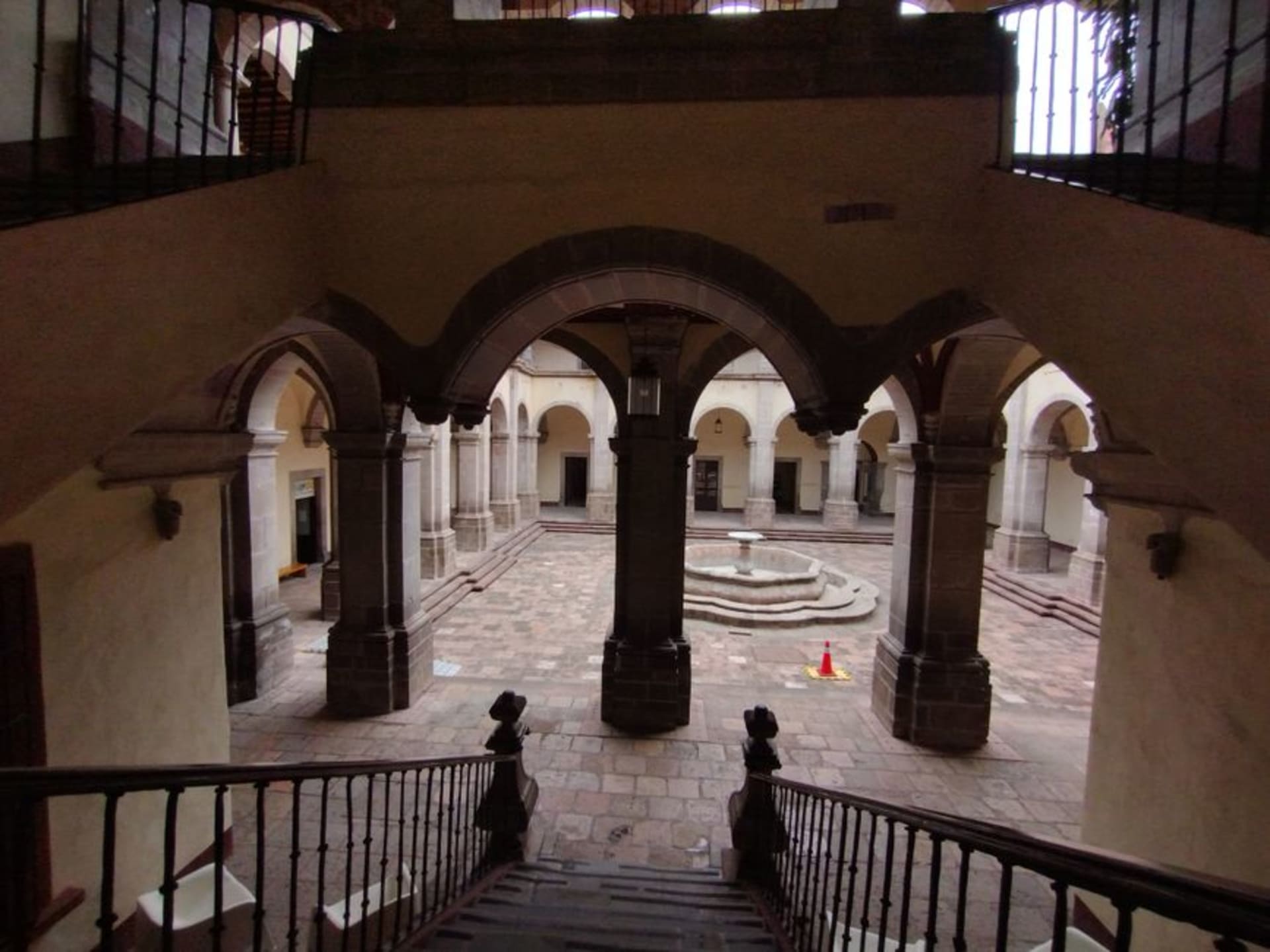 The stone facade of the 16th-century Dominican monastery in Epazoyucan with open-air chapel arches casting long morning shadows across the atrium