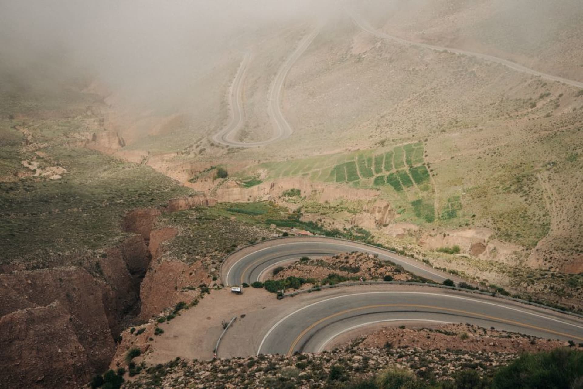 Fog pouring into a barranca gorge along El Espinazo del Diablo on old Highway 40, pine forest clinging to near-vertical canyon walls above a void with no visible floor