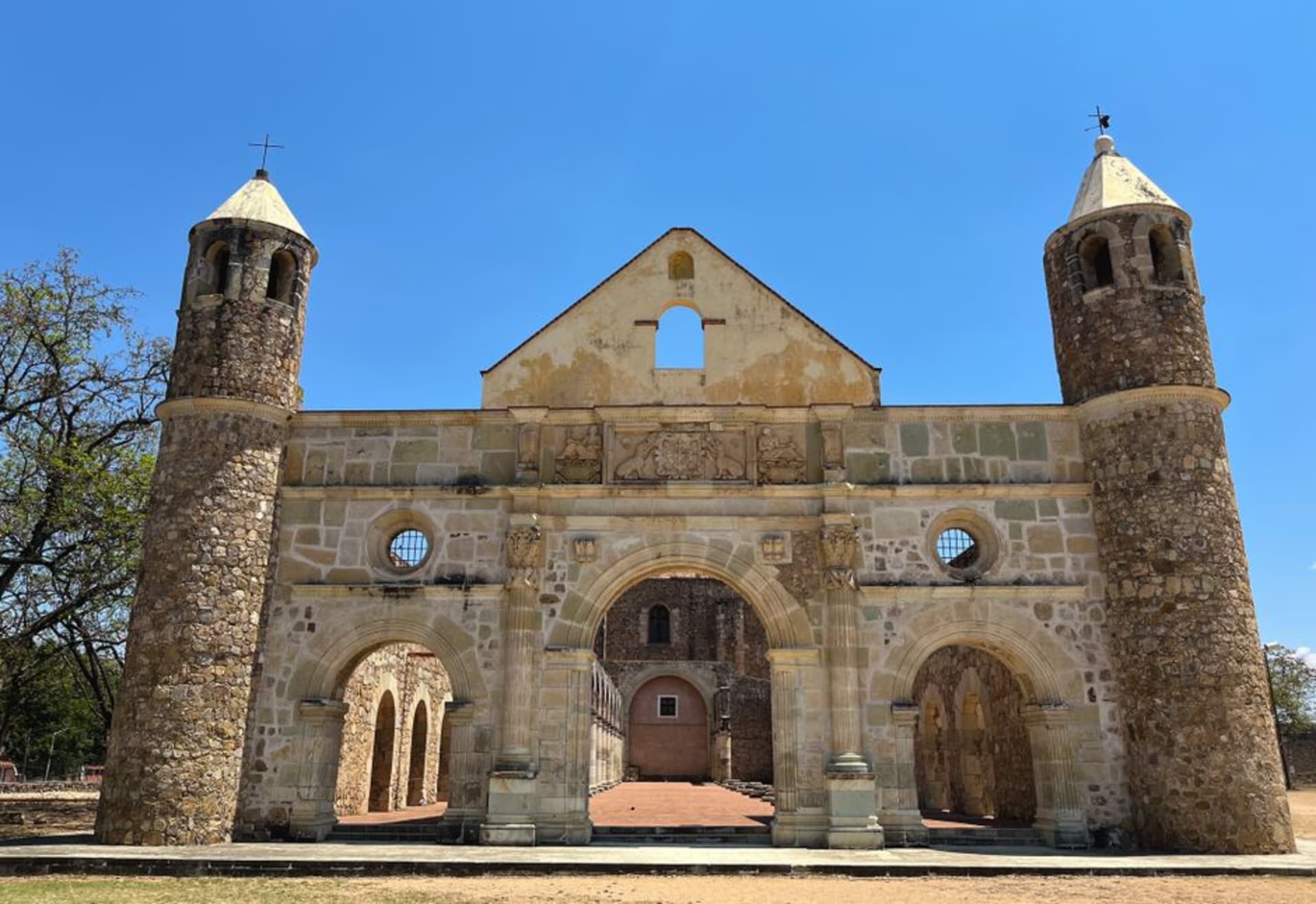 Shaded plaza of Hecelchakán with the whitewashed facade of the colonial church of San Francisco de Asís visible through old laurel trees