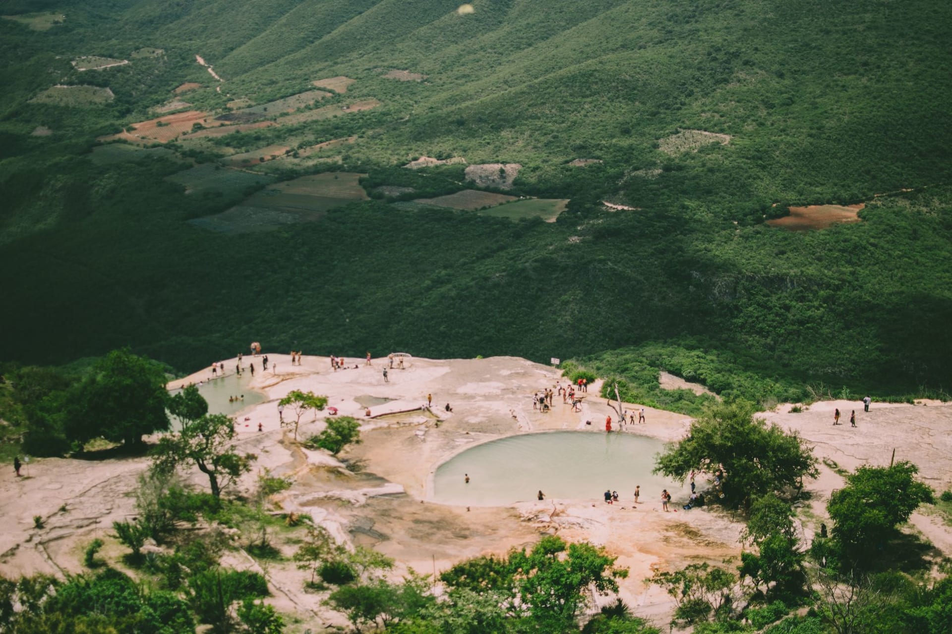 The white calcified cliff of Hierve el Agua spilling down a mountainside above natural pools and a green Oaxacan valley