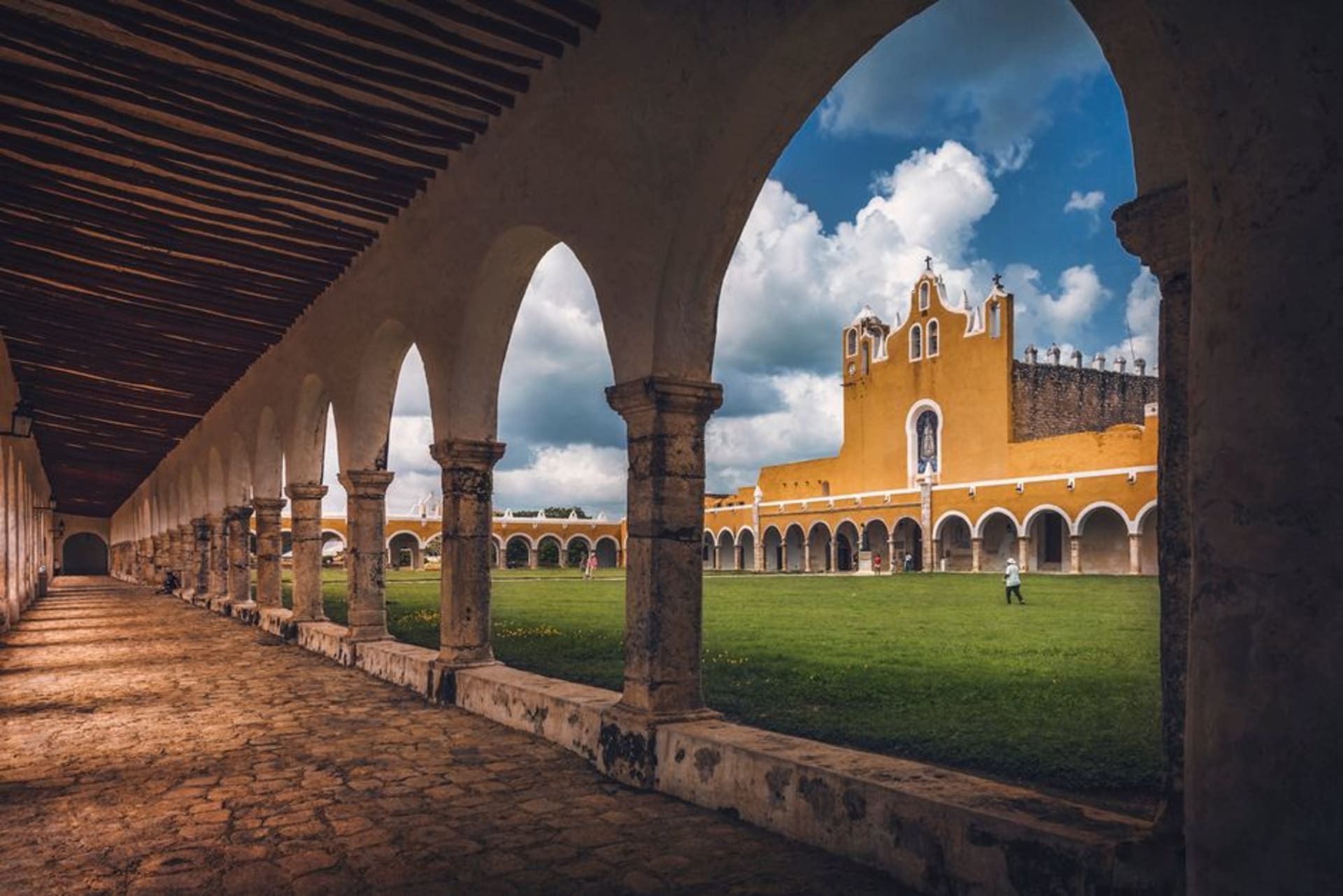 The wide atrium of Huejotzingo's Franciscan ex-convent on a clear winter morning, its pale stone facade catching low Sierra Nevada light above an empty plaza