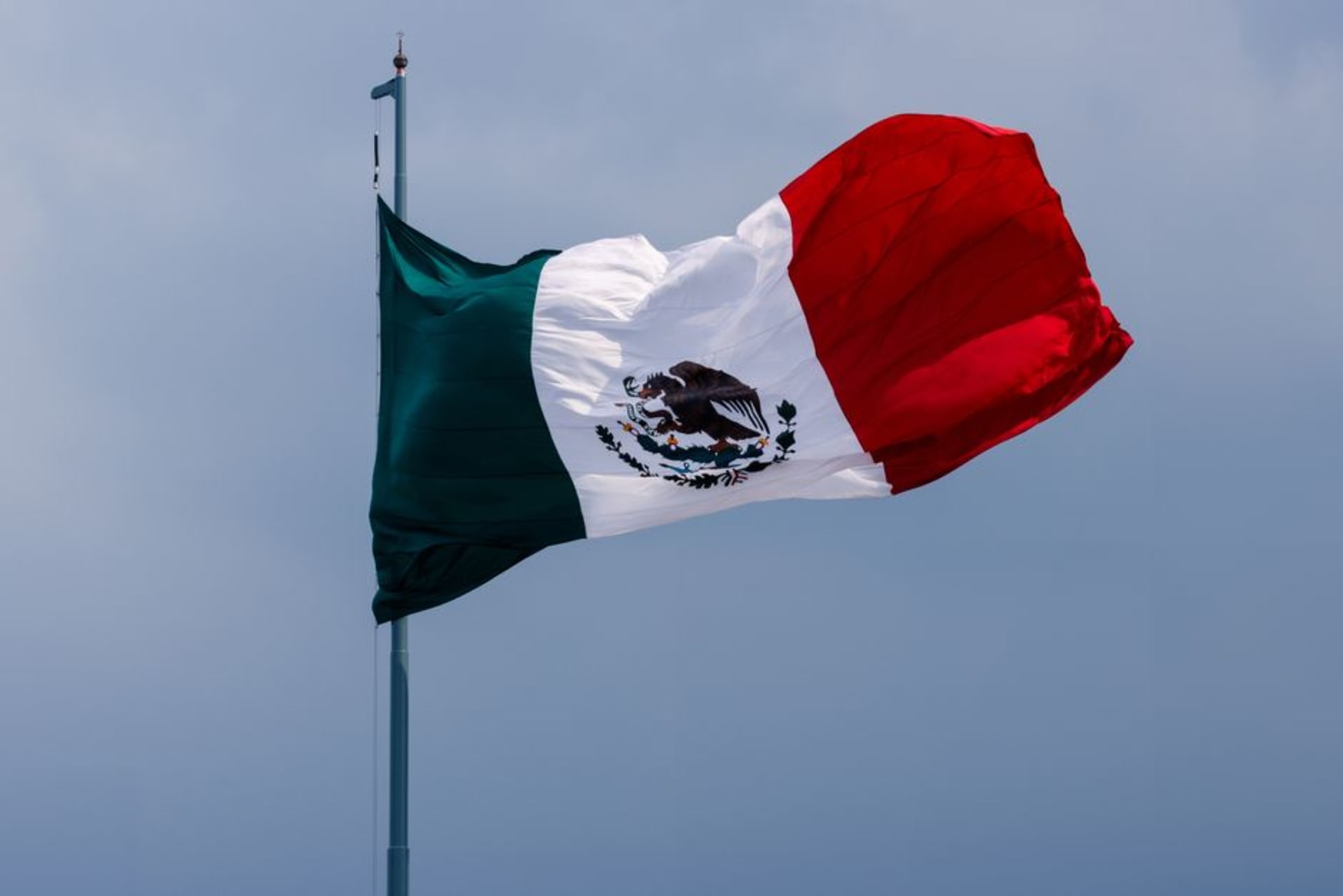 The Monumento a la Bandera rising above Iguala's vast central plaza at dusk, the Mexican tricolor lit against a darkening Guerrero sky