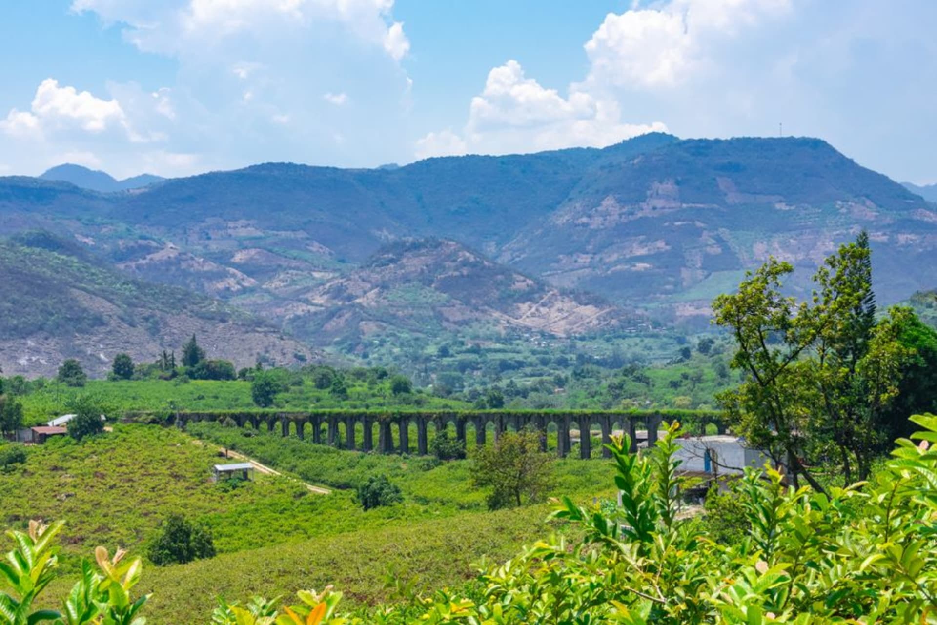 The small town of Indaparapeo east of Morelia, low houses and a church tower with agave and farm fields running up toward the hills behind