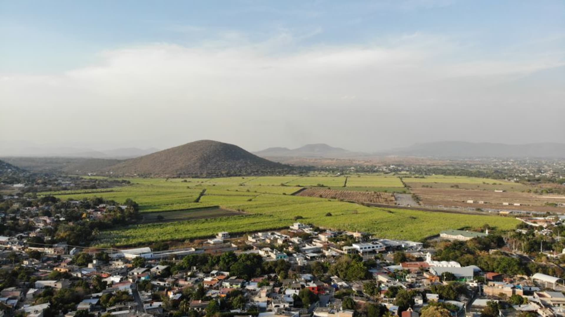 The central plaza of Ometepec on market day, crowded with canvas tarps and vendors in the early morning light, the sierra visible in the distance