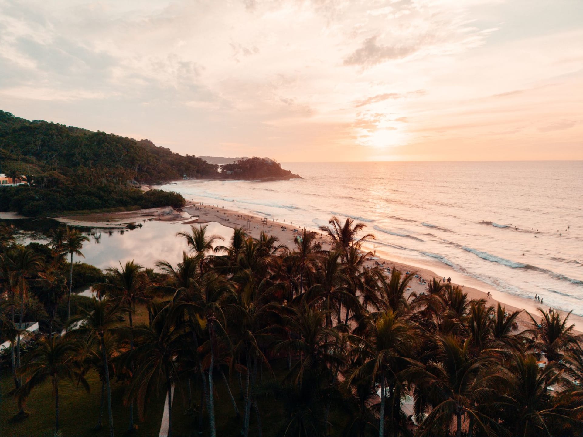 The surf break at Punta Mita with a clean head-high wave peeling left, the Marieta Islands visible in the distance, the horizon flat and blue under a clear December sky