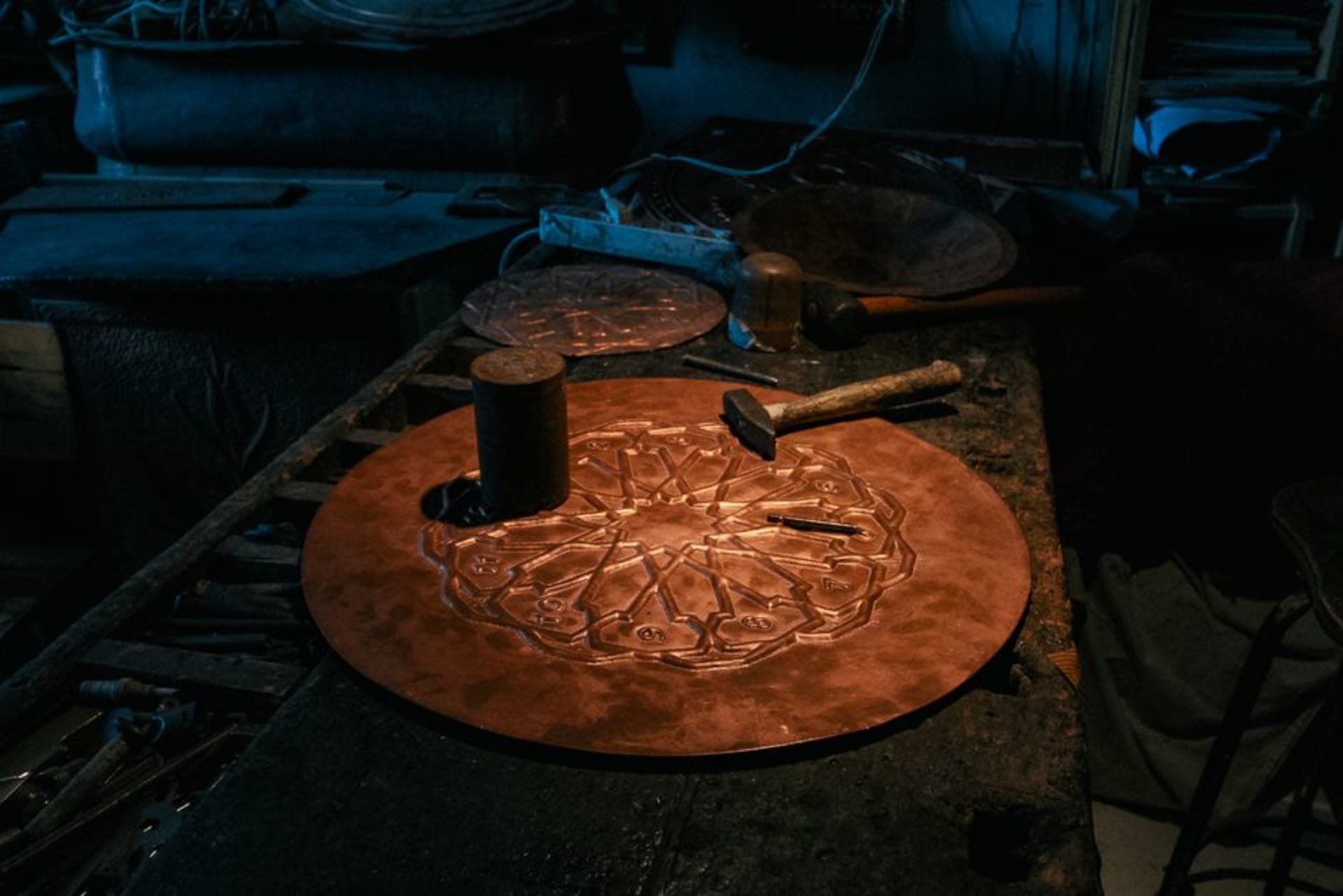 A copper workshop in Santa Clara del Cobre with hammered vessels hanging from the walls and an artisan working at an anvil
