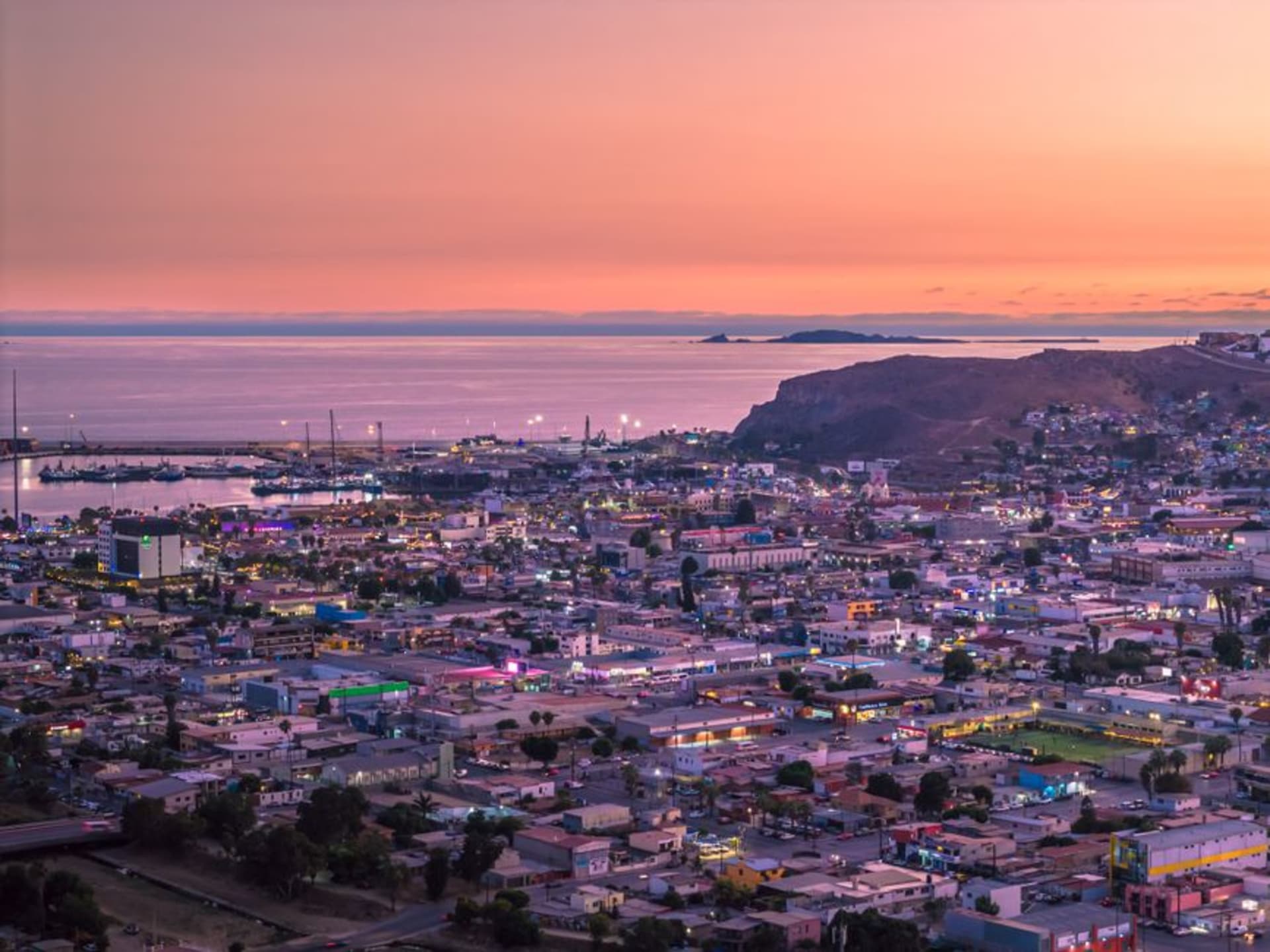 Pastel clapboard houses from the French mining era climbing the red-oxide hills above Santa Rosalía, the Sea of Cortés shimmering flat and silver in the distance