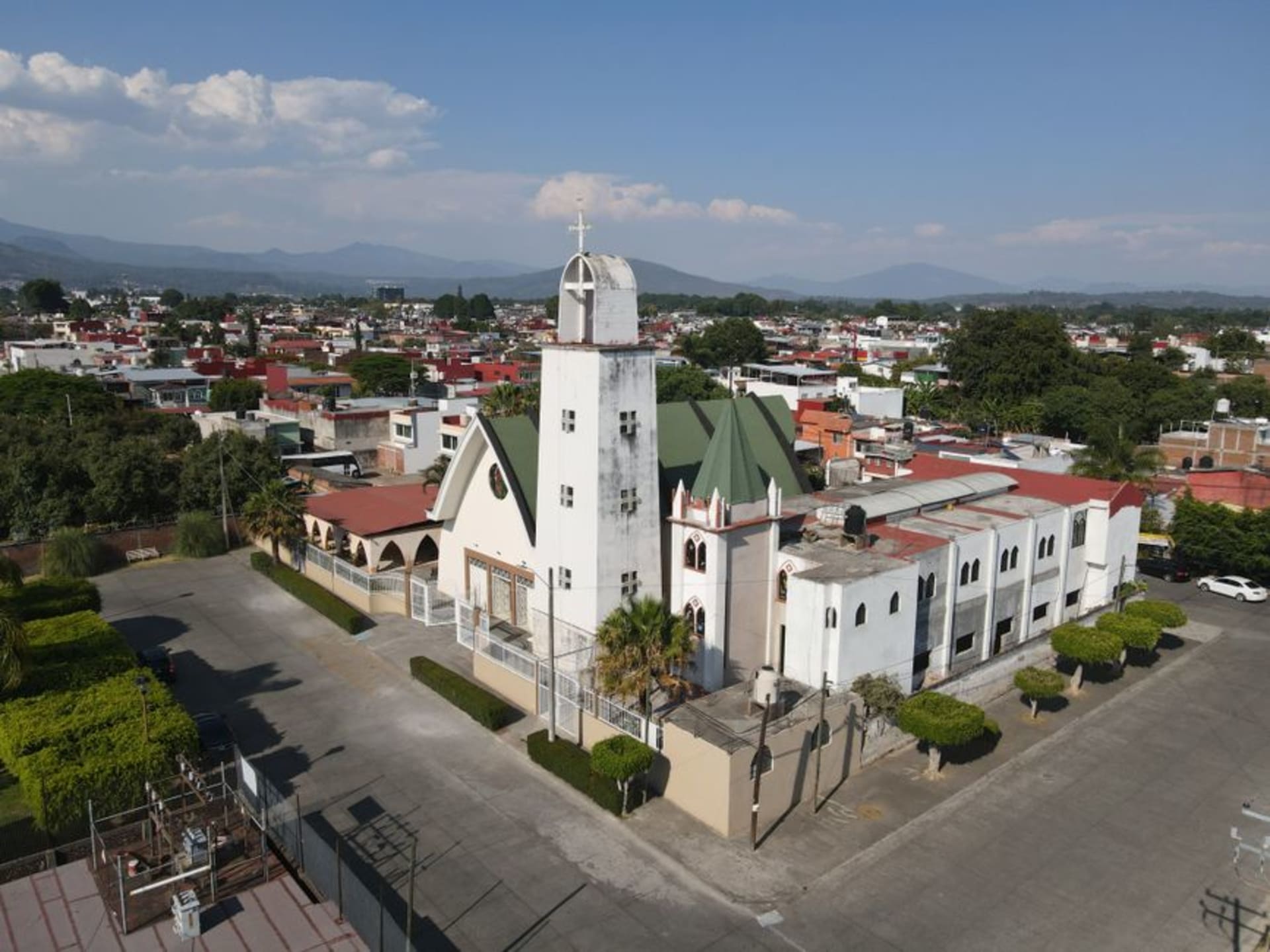 Cobblestone street in Tacámbaro climbing toward the pale stone Franciscan convent, avocado-covered hills filling the valley behind