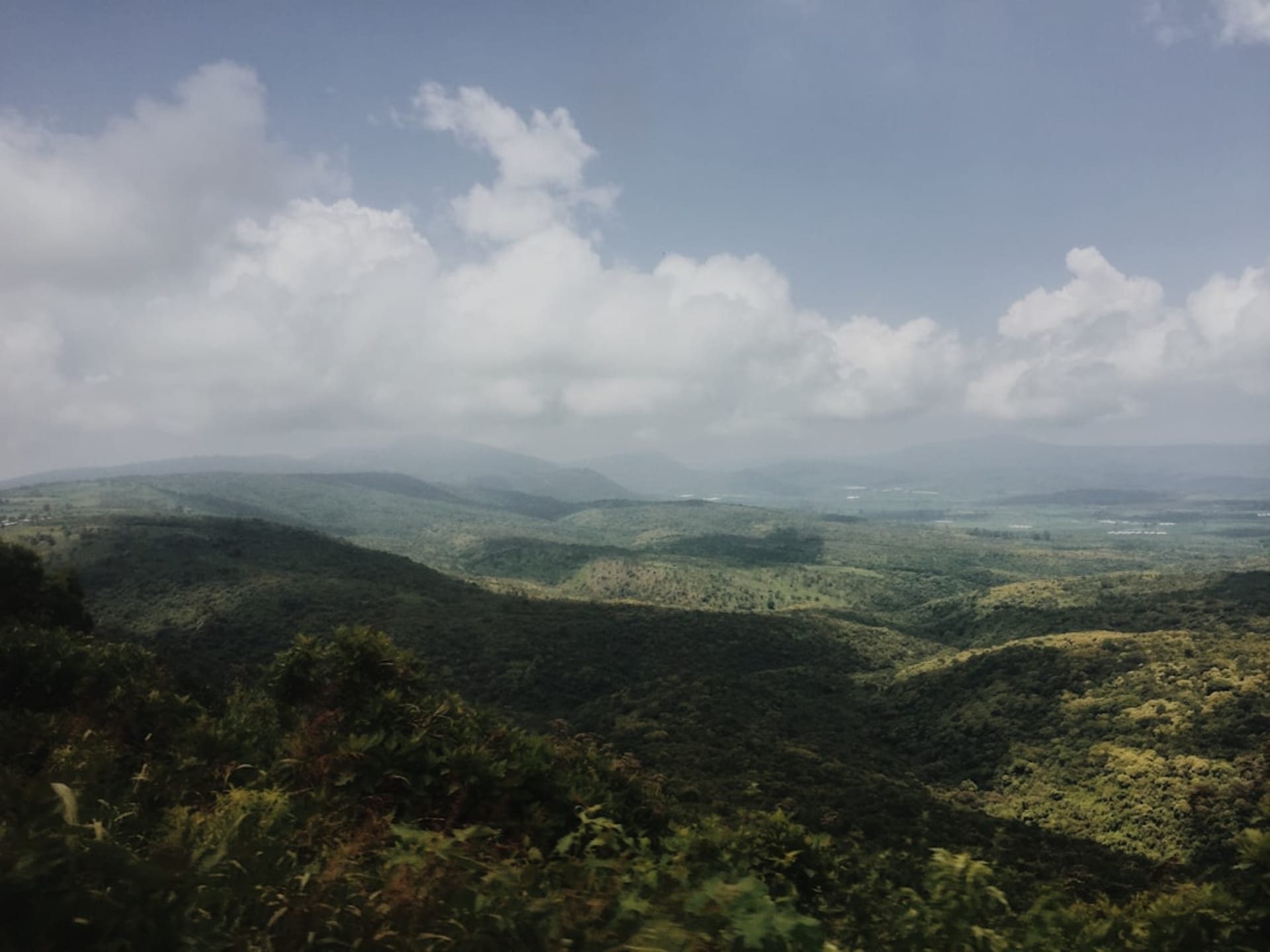 The green farmland of the upper Lerma valley around Temascalcingo, cultivated fields and low hills under a soft highland sky, the modest town nestled below