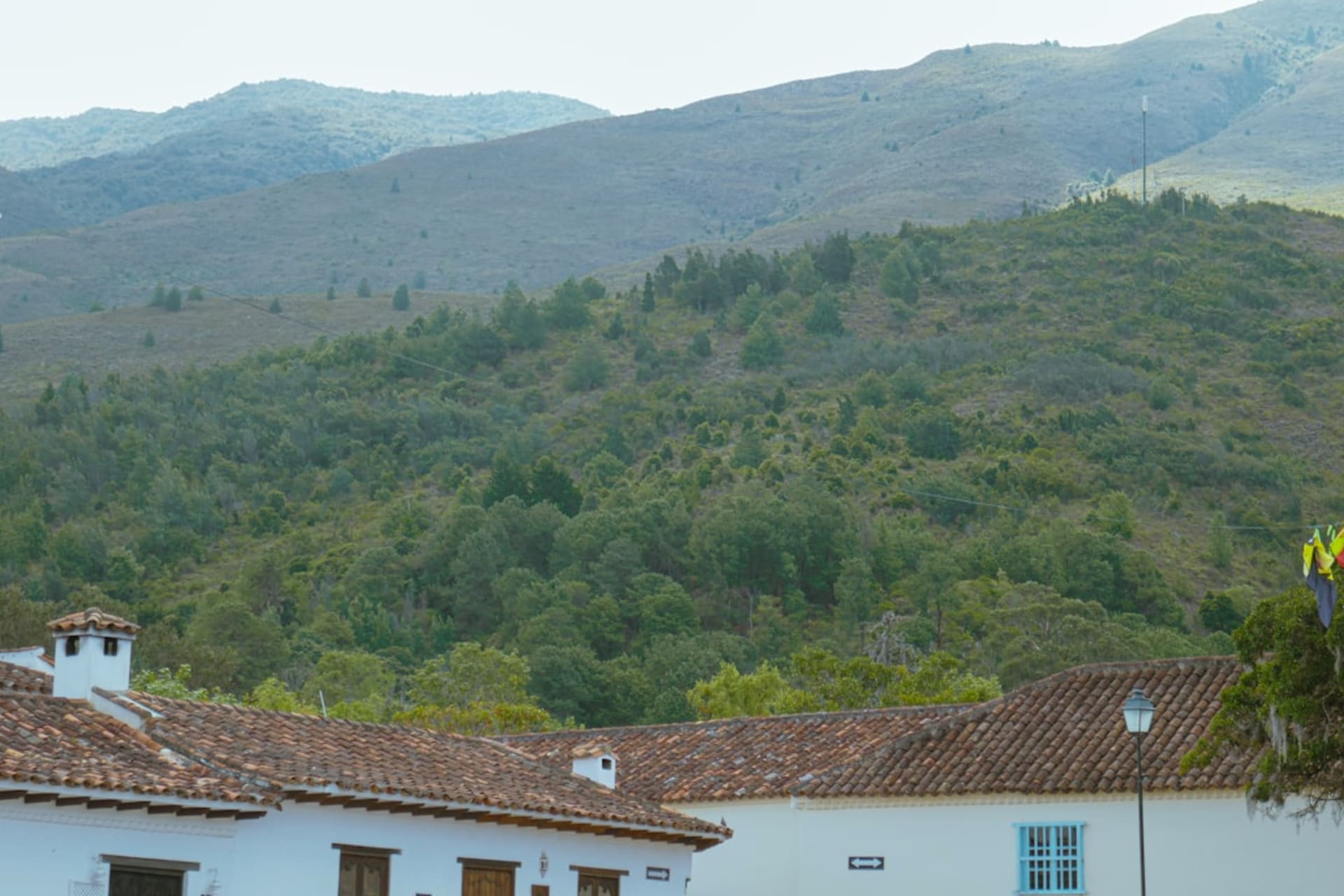 Fog settling over the colonial church of San Juan Bautista in Tetela de Ocampo, with green sierra slopes dissolving into grey behind the bell tower