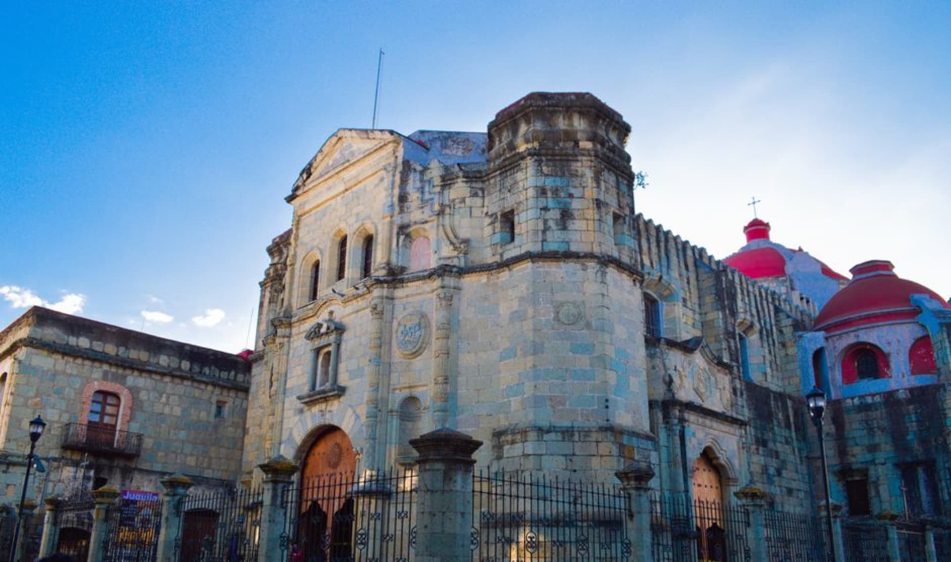 The main plaza of Tlaxiaco with the 16th-century Templo de la Asunción rising behind market stalls on a bright Saturday morning